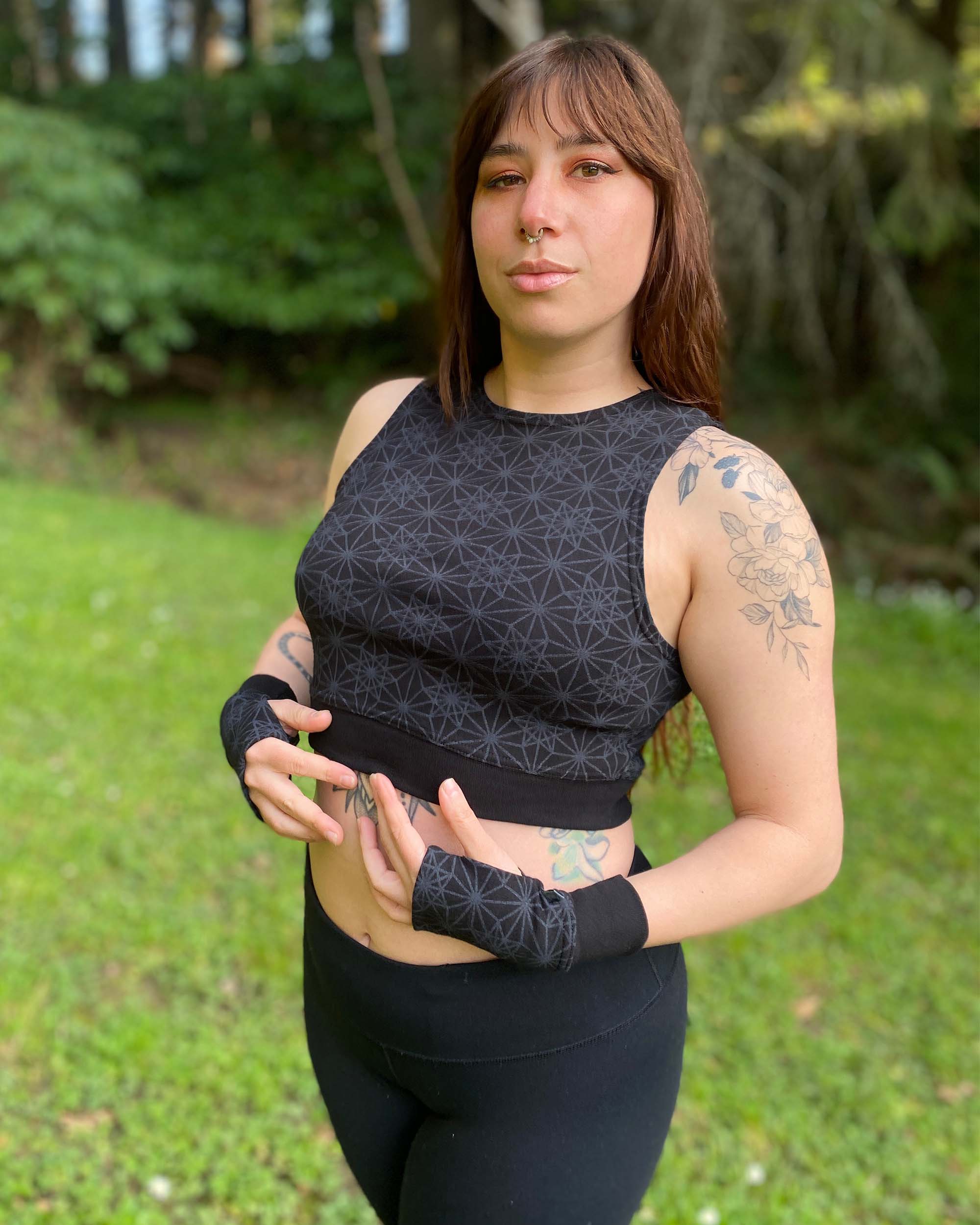Organic cotton crop top, black fabric with sacred geometry print, front left side view on female model.