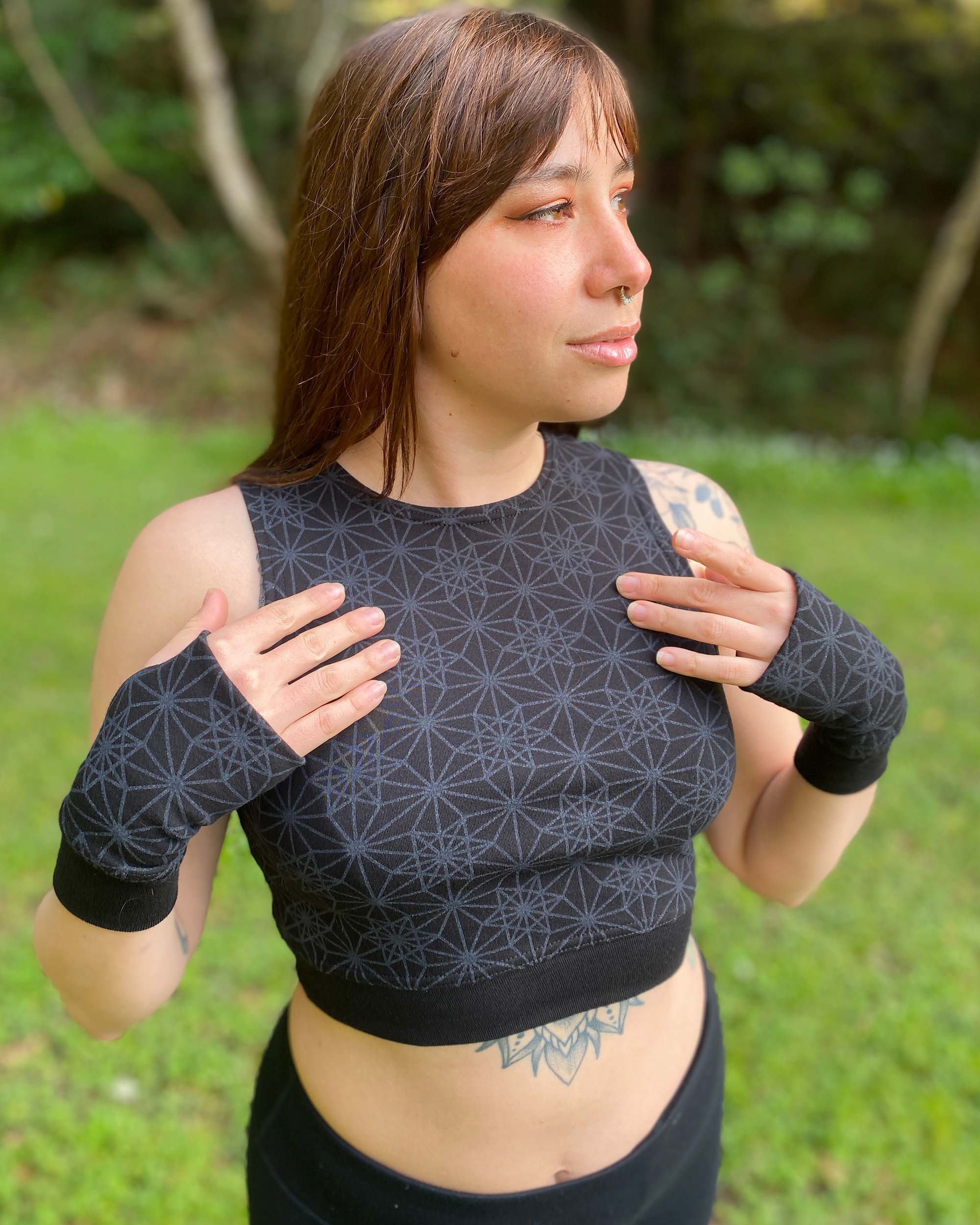 Organic cotton crop top, black fabric with sacred geometry print, front right side view on female model.