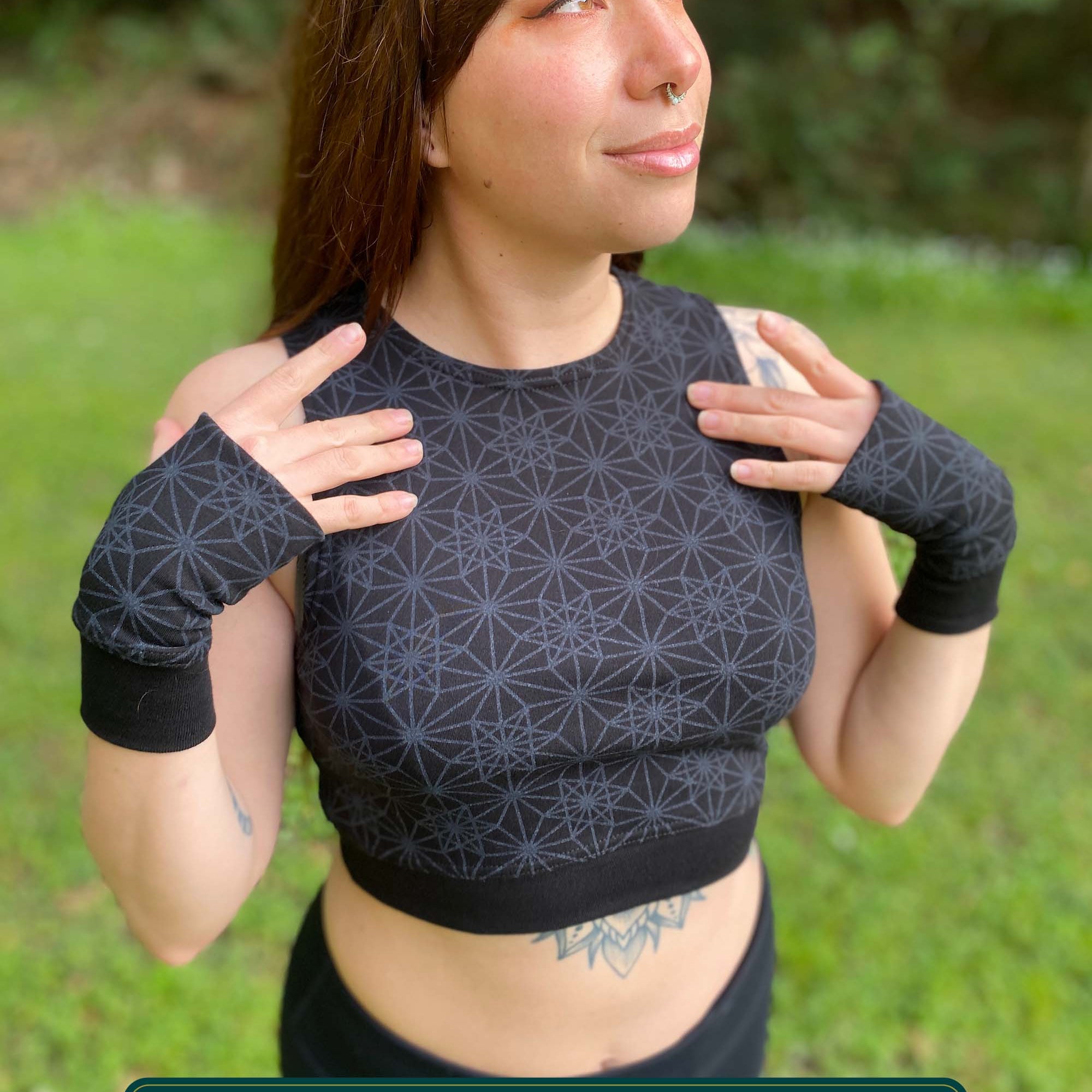 Organic cotton crop top, black fabric with sacred geometry print, front view on female model.