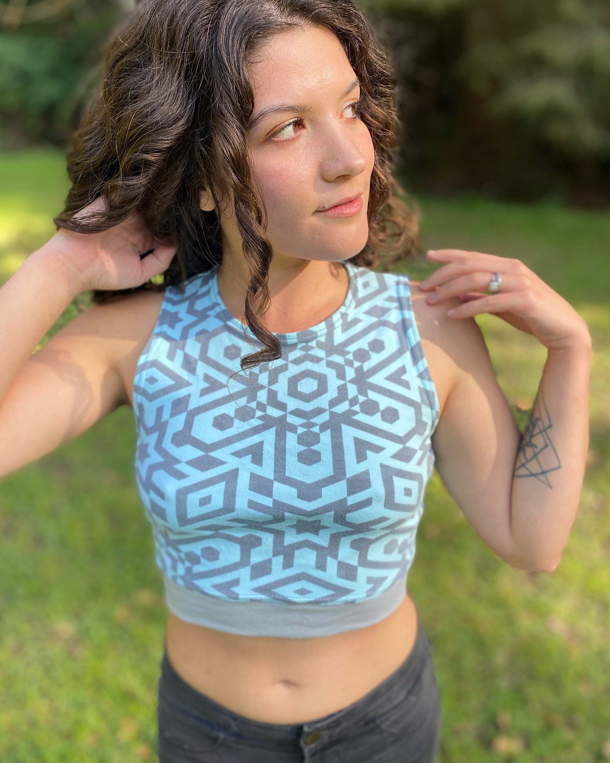 Organic cotton crop top, mint colored fabric with grey geometric print, front right view on female model.