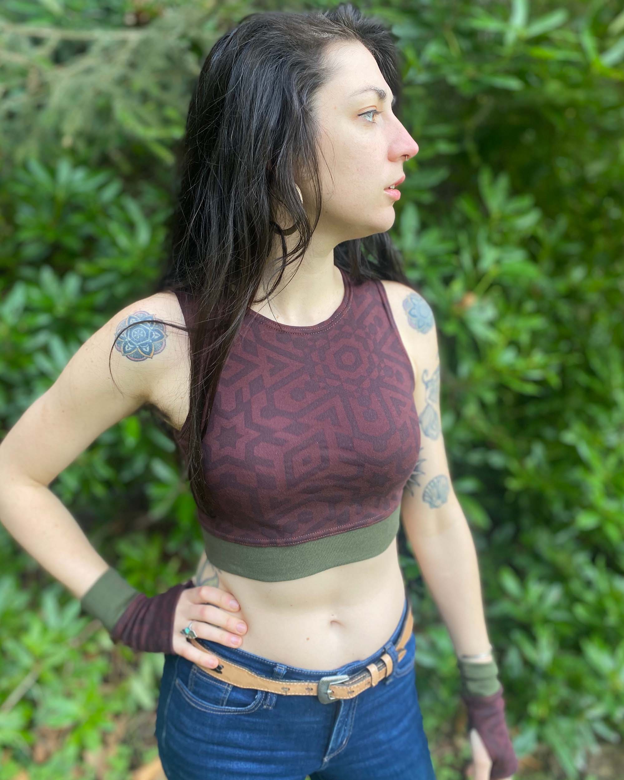 Organic cotton crop top, reddish brown fabric with geometric print, front side view on model in nature.