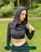 A woman wearing an organic cotton black crop hoodie with geometric print, with matching joggers, front view in a outdoor setting.