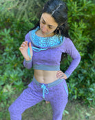 A woman wearing an organic cotton lavender crop hoodie with geometric print, cowl hood and long sleeves, front view in nature.