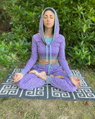 A woman meditating in nature, wearing an organic cotton lavender crop hoodie with geometric print, cowl hood and long sleeves.