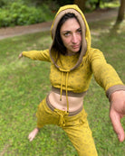 A woman doing yoga wearing an organic cotton yellow crop hoodie with geometric print, with matching joggers.