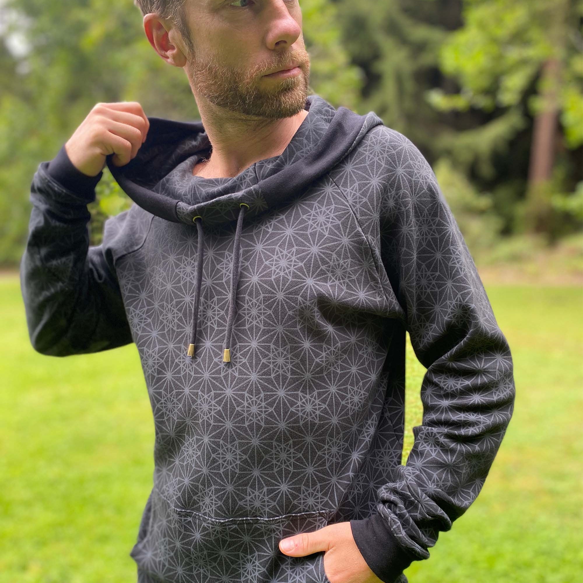 Organic cotton extra long unisex hoodie, black with sacred geometry print, left side view of male model.