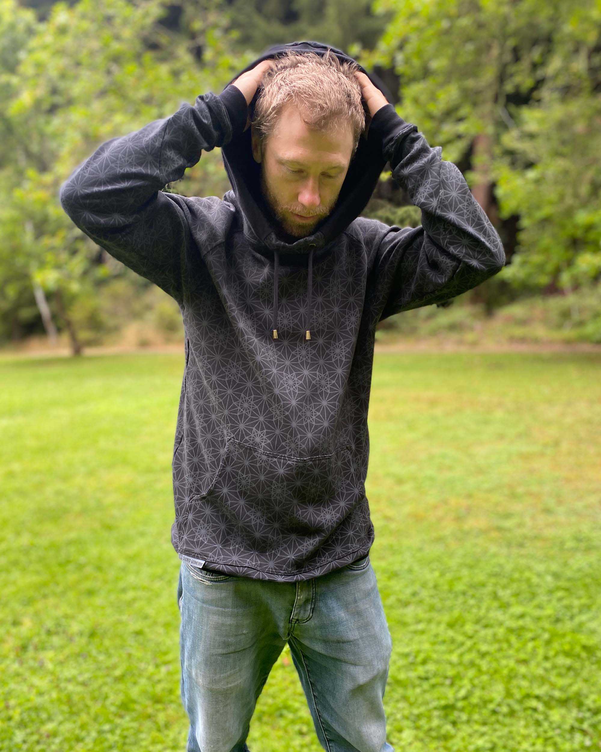 Organic cotton extra long unisex hoodie, black with geometric print, front view of male model.