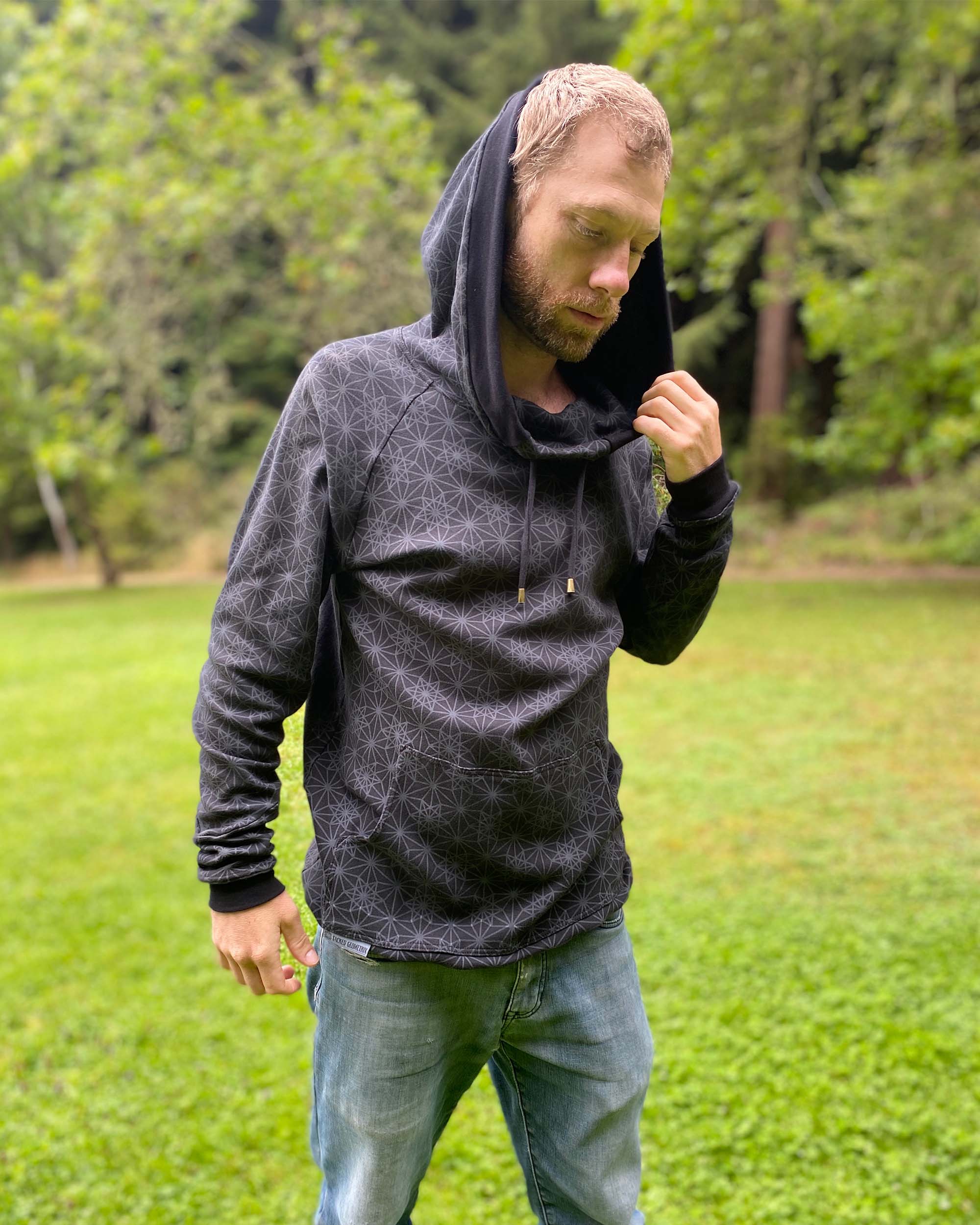 Organic cotton extra long unisex hoodie, black with sacred geometry print, right side view of male model.