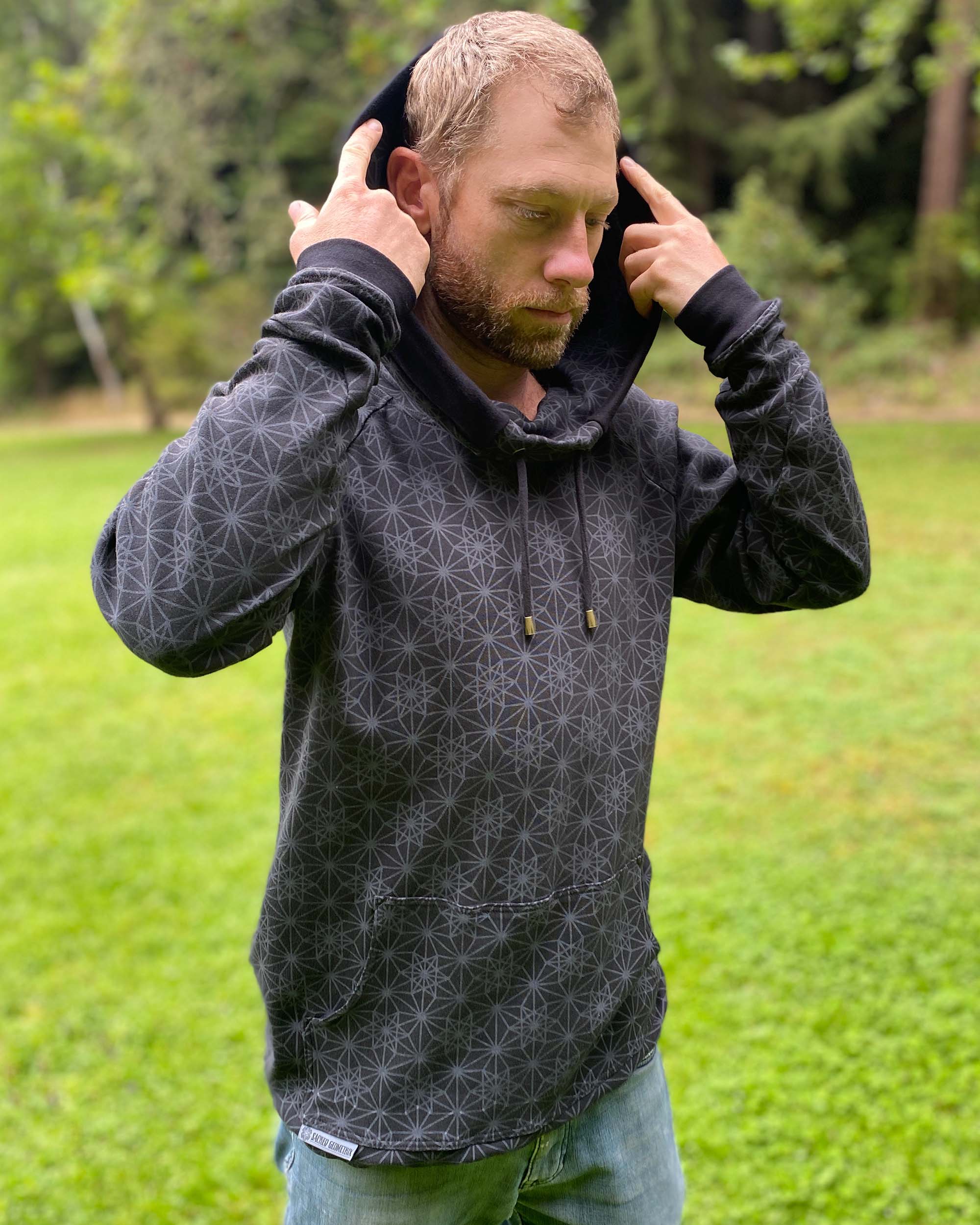 Organic cotton extra long unisex hoodie, black with geometric print, right side front view of male model.