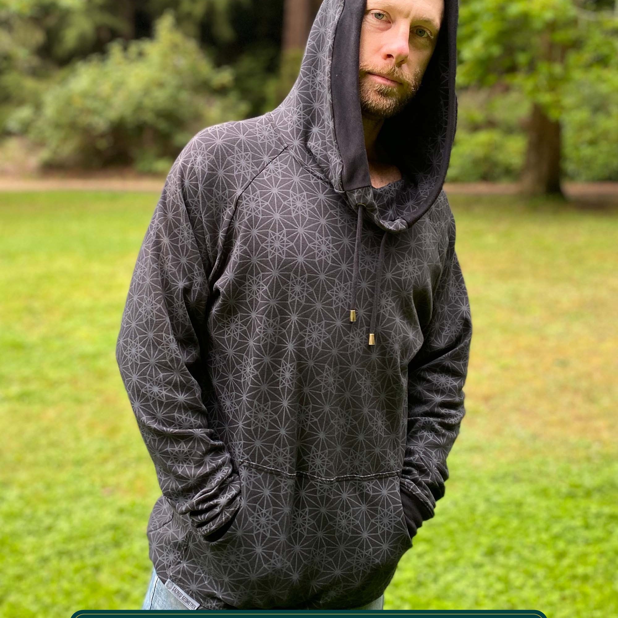 Organic cotton extra long unisex hoodie, black with sacred geometry print, front view of male model.
