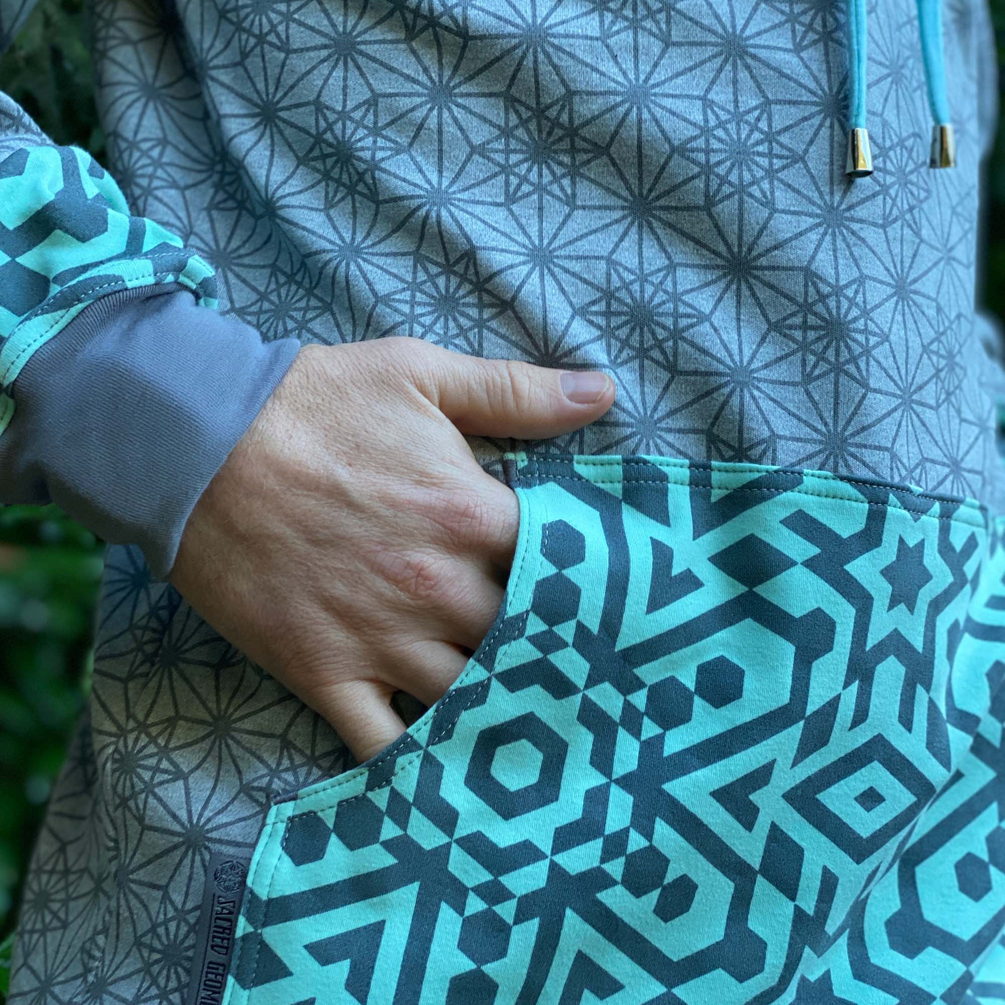 Organic cotton hoodie, grey fabric and mint colored accents, close up of pocket details.