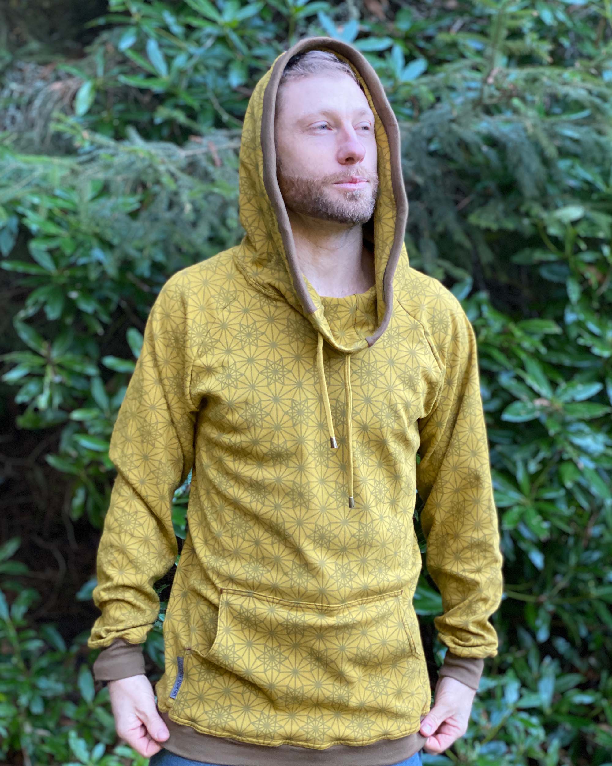 Organic cotton extra long unisex hoodie, yellow fabric with geometric print, front view in low lighting.