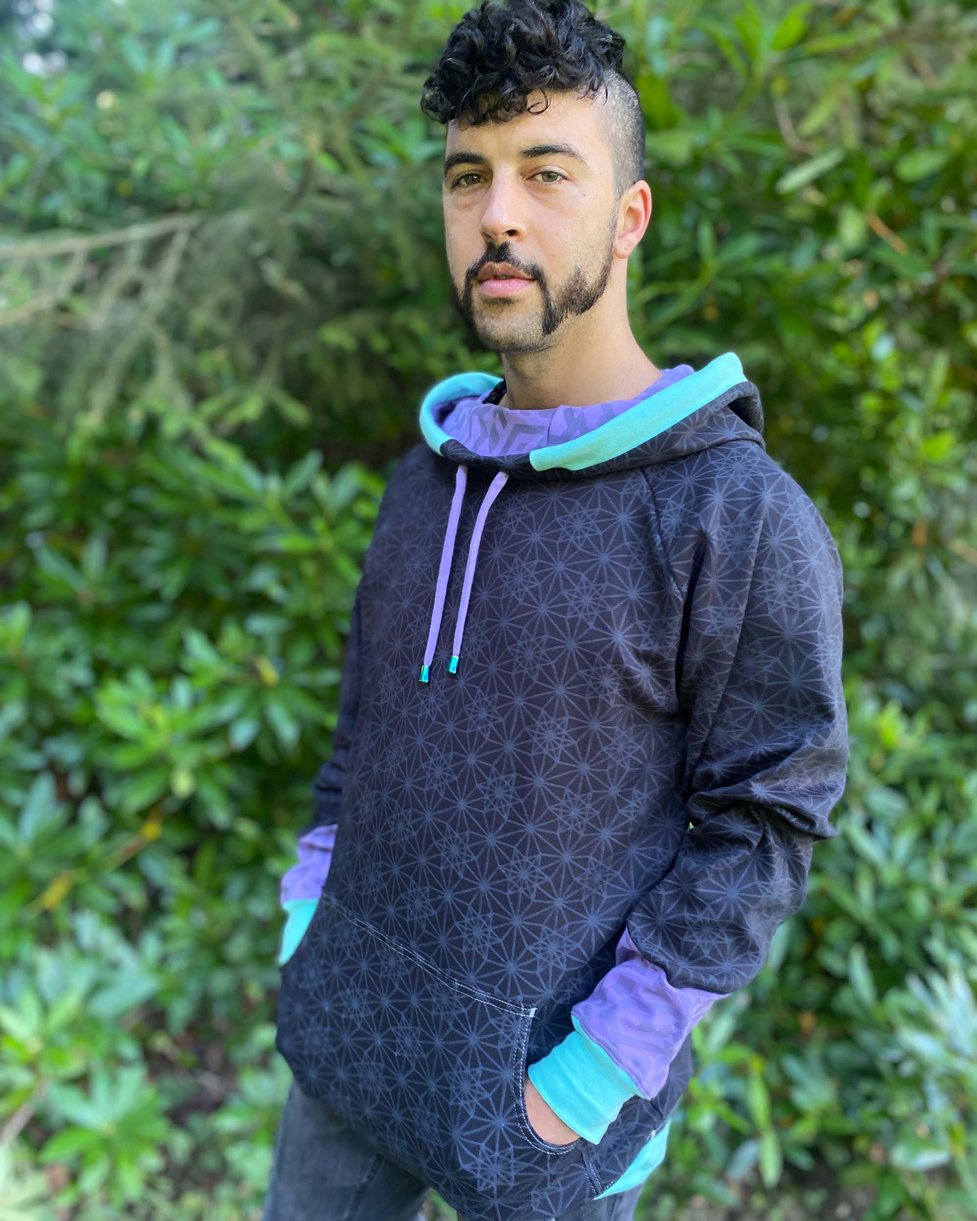 Organic cotton hoodie, black with sacred geometry print, left side view of male model.