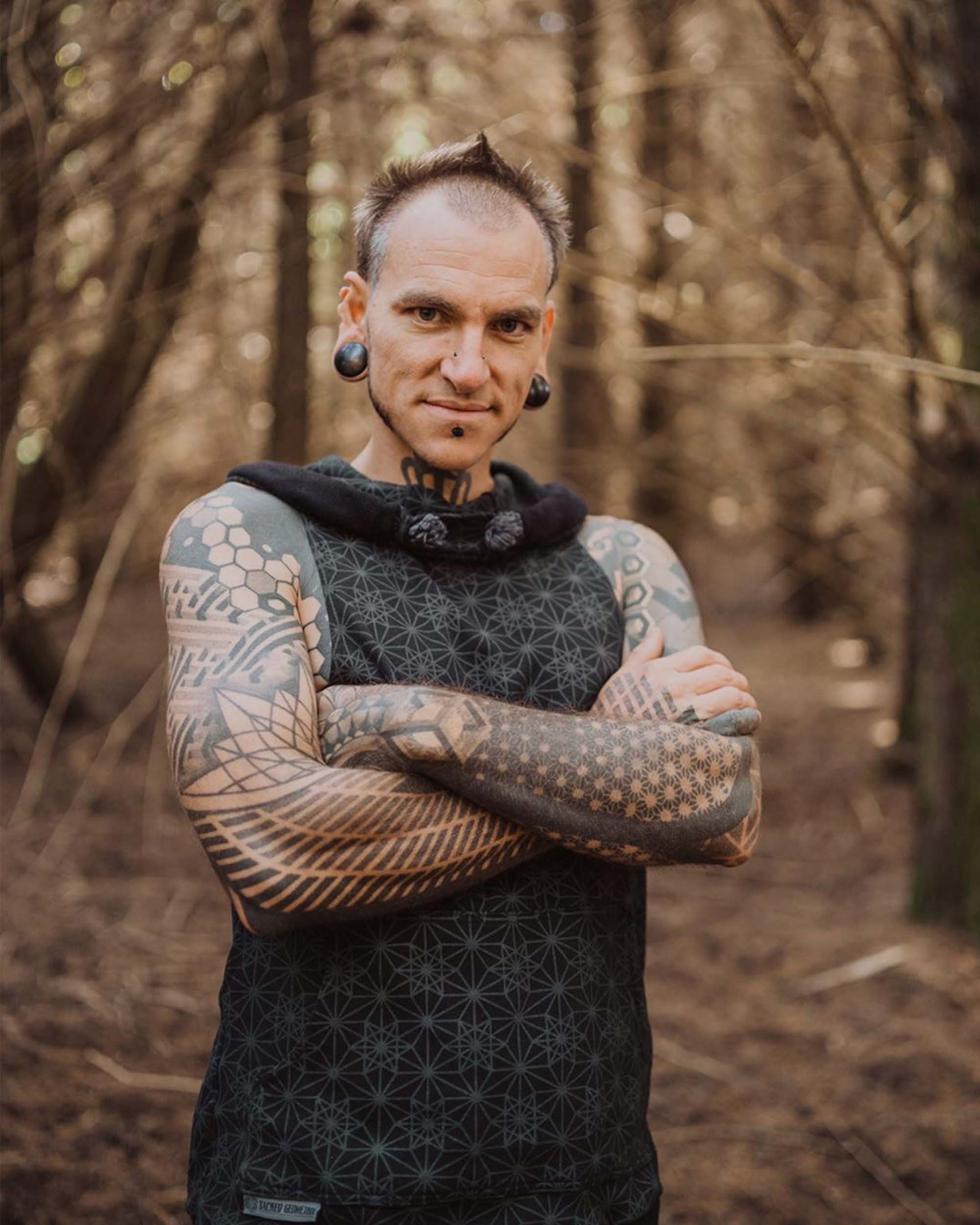 Organic cotton sleeveless hoodie, black with geometric print, close up front view on male model.