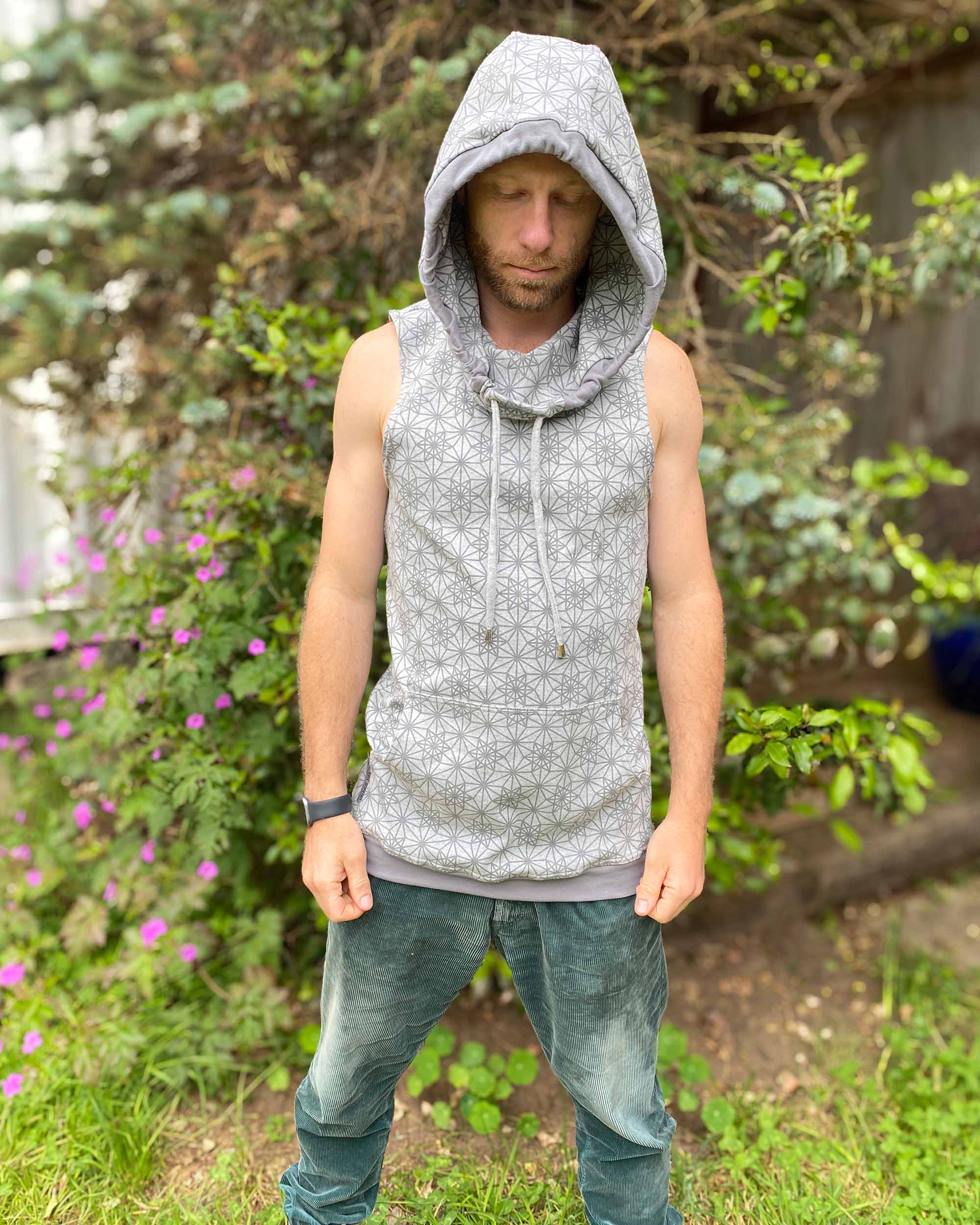 Organic cotton sleeveless hoodie, grey with geometric print, front view on male model in nature.