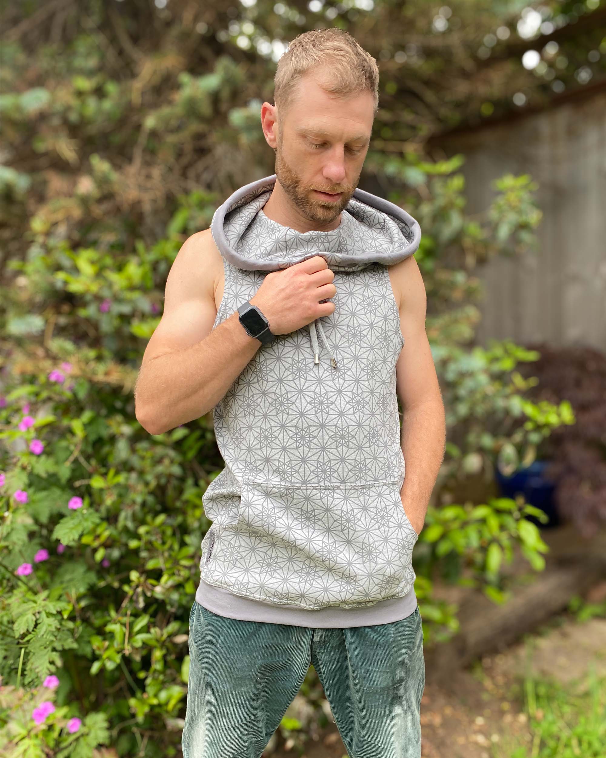 Organic cotton sleeveless hoodie, grey with geometric print, front detail view of fabric.