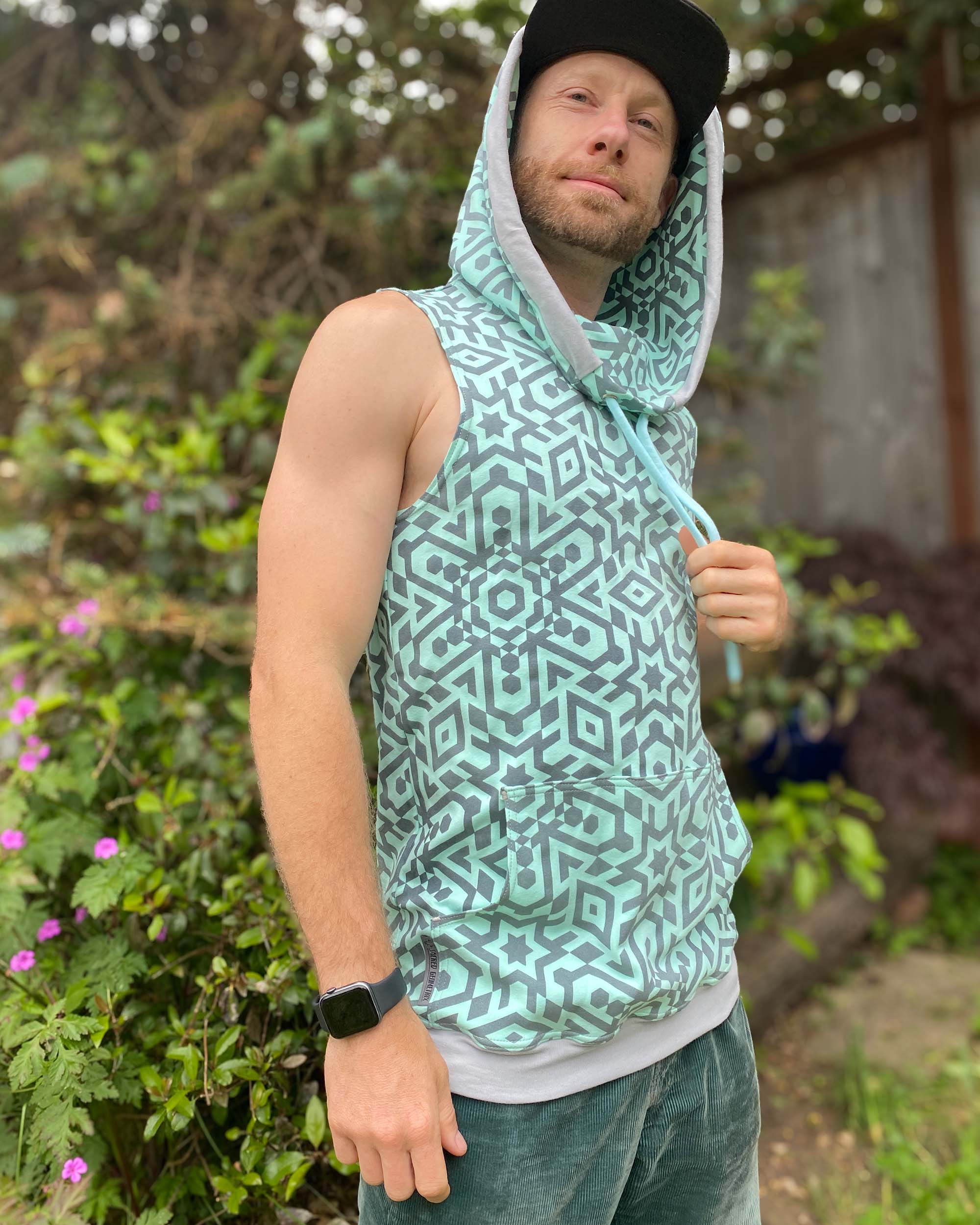 Organic cotton sleeveless hoodie, mint with geometric print fabric, front right view on male model.