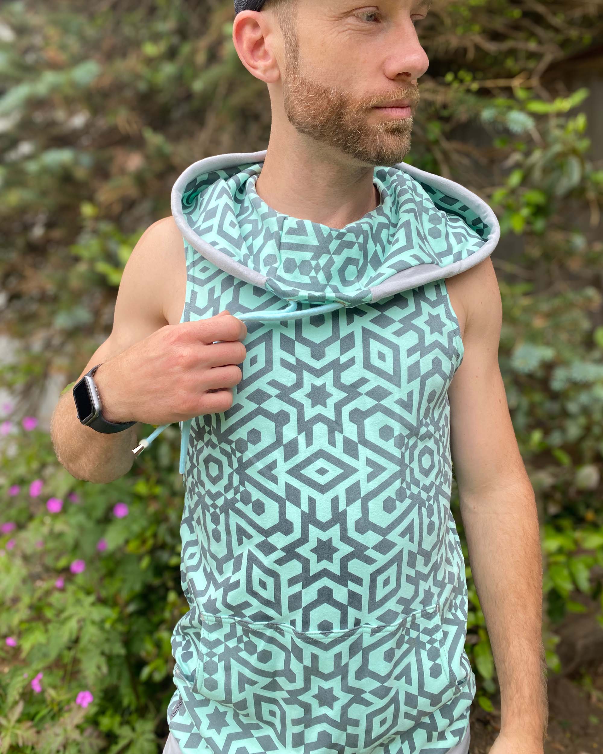 Organic cotton hooded tank top, mint with geometric print fabric, front view on male model.