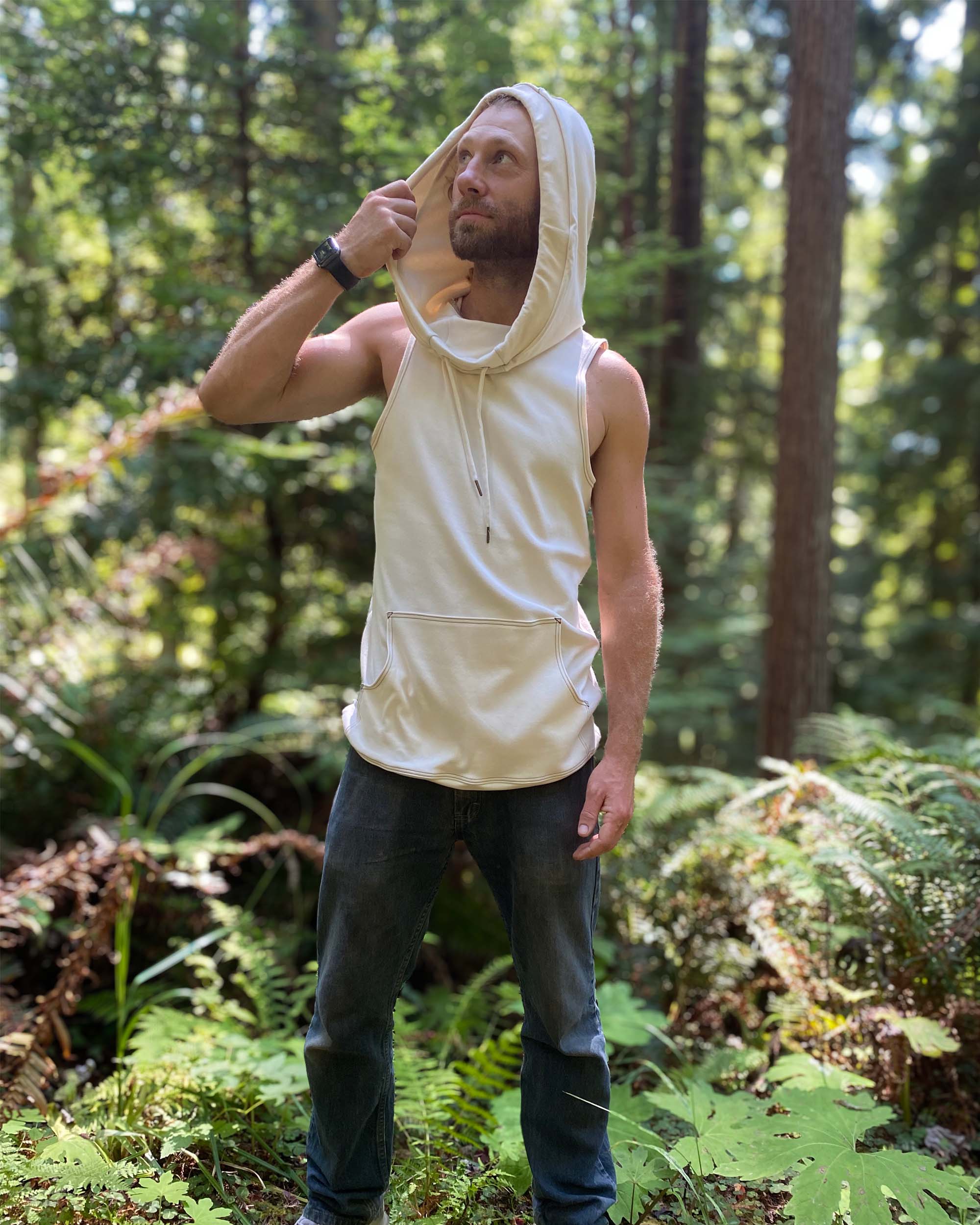 Organic cotton sleeveless hoodie, undyed fabric, front left side view on male model, hood up.