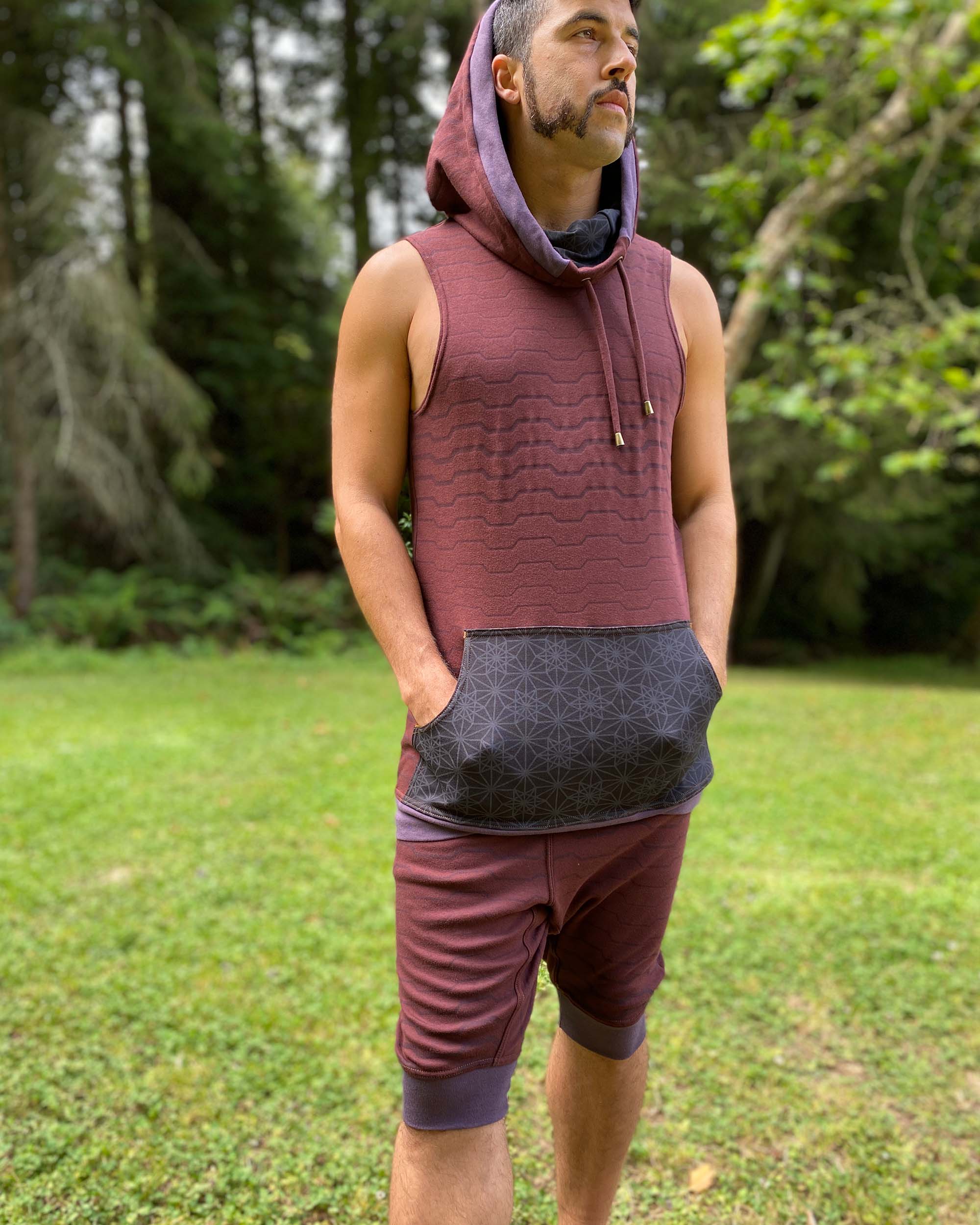 Organic cotton hooded tank top, brown with black accents and geometric print, front view on male model, hood up.
