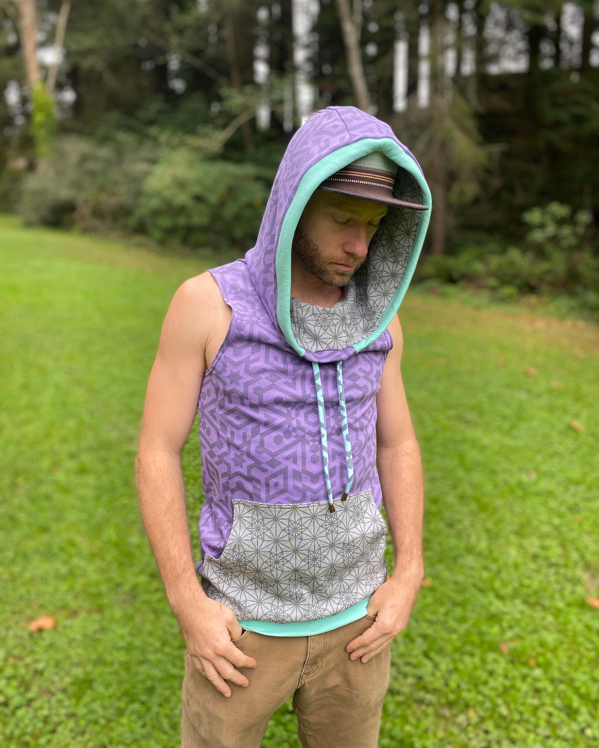 Organic cotton hooded tank top, lavender with geometric printed fabric, front view on male model, hood up.
