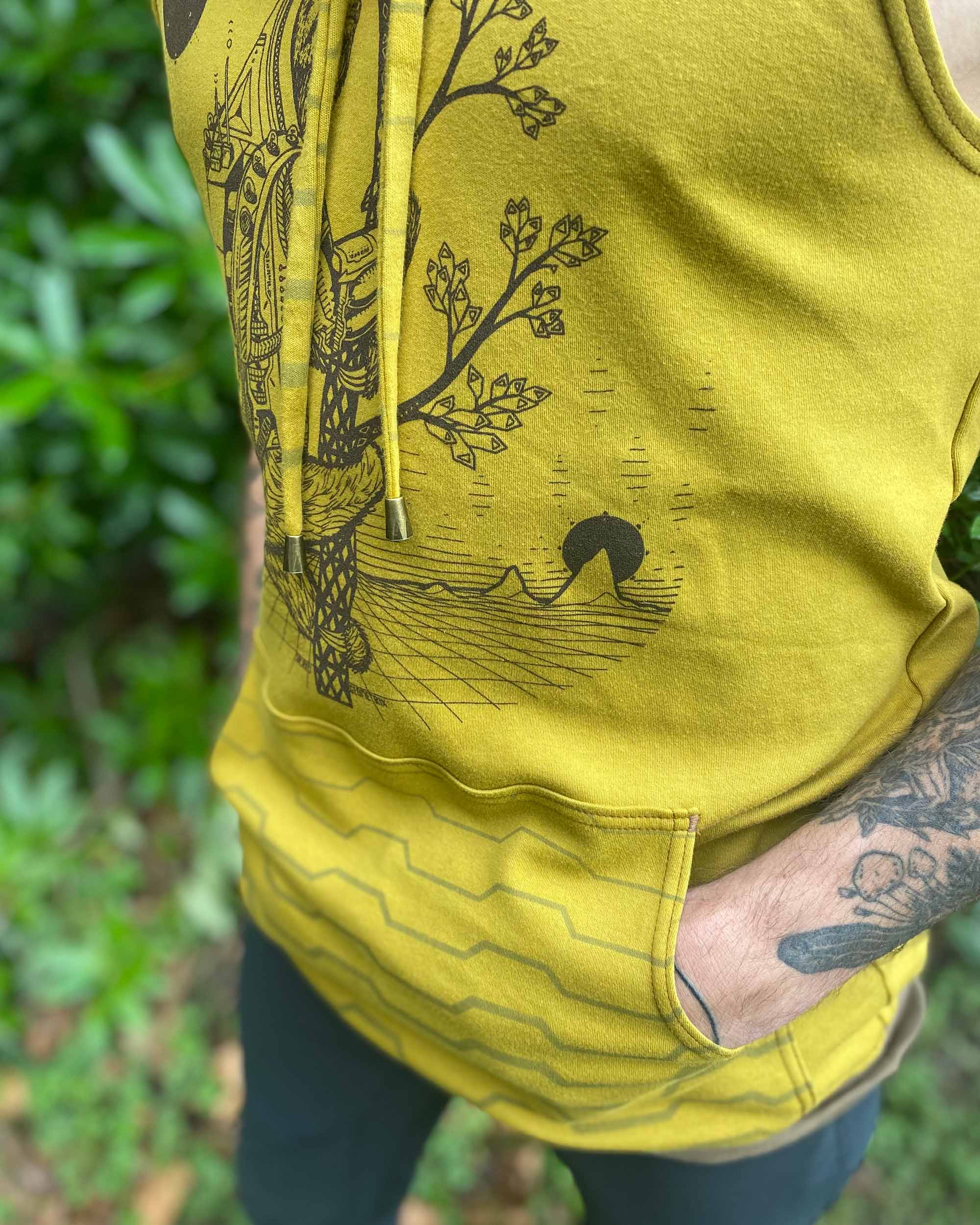 Organic cotton sleeveless hoodie, yellow fabric with sloth graphic, close up view of pocket.