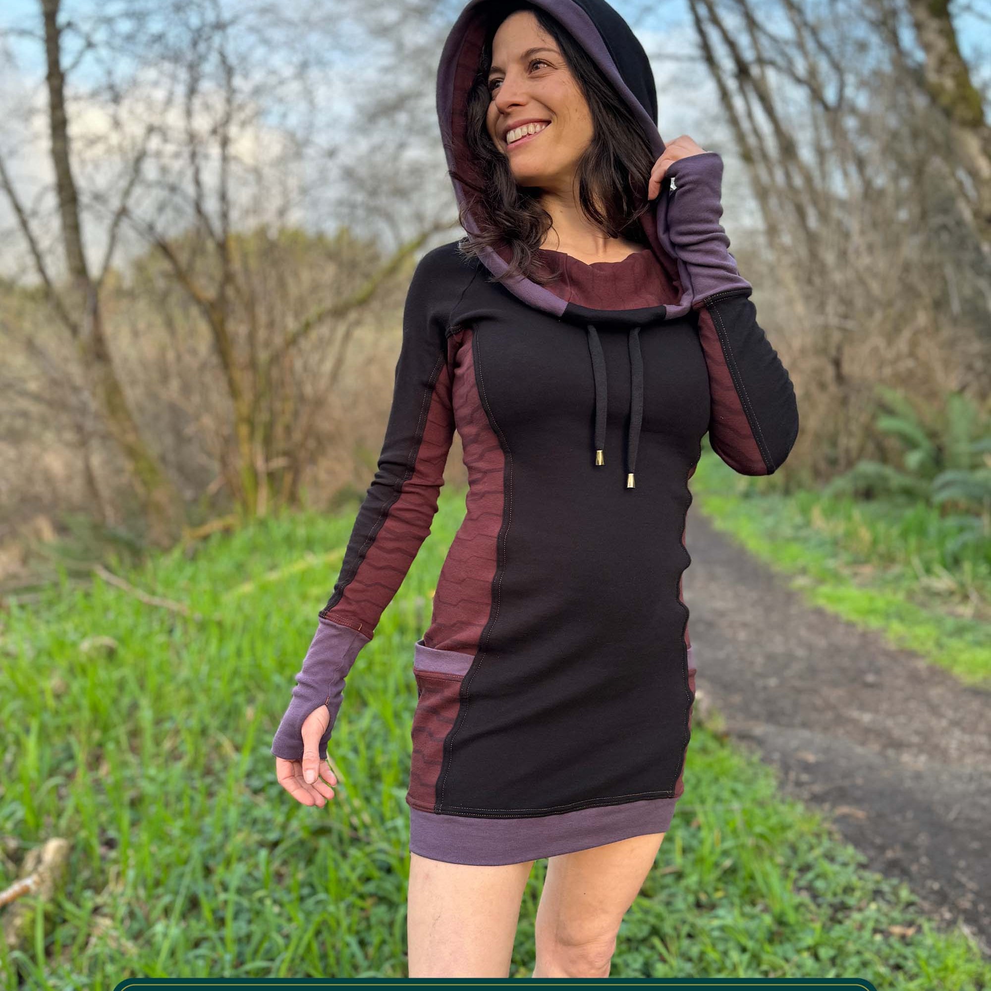 Organic cotton hooded tunic dress, black with geometric brown fabric accents, front view on model.