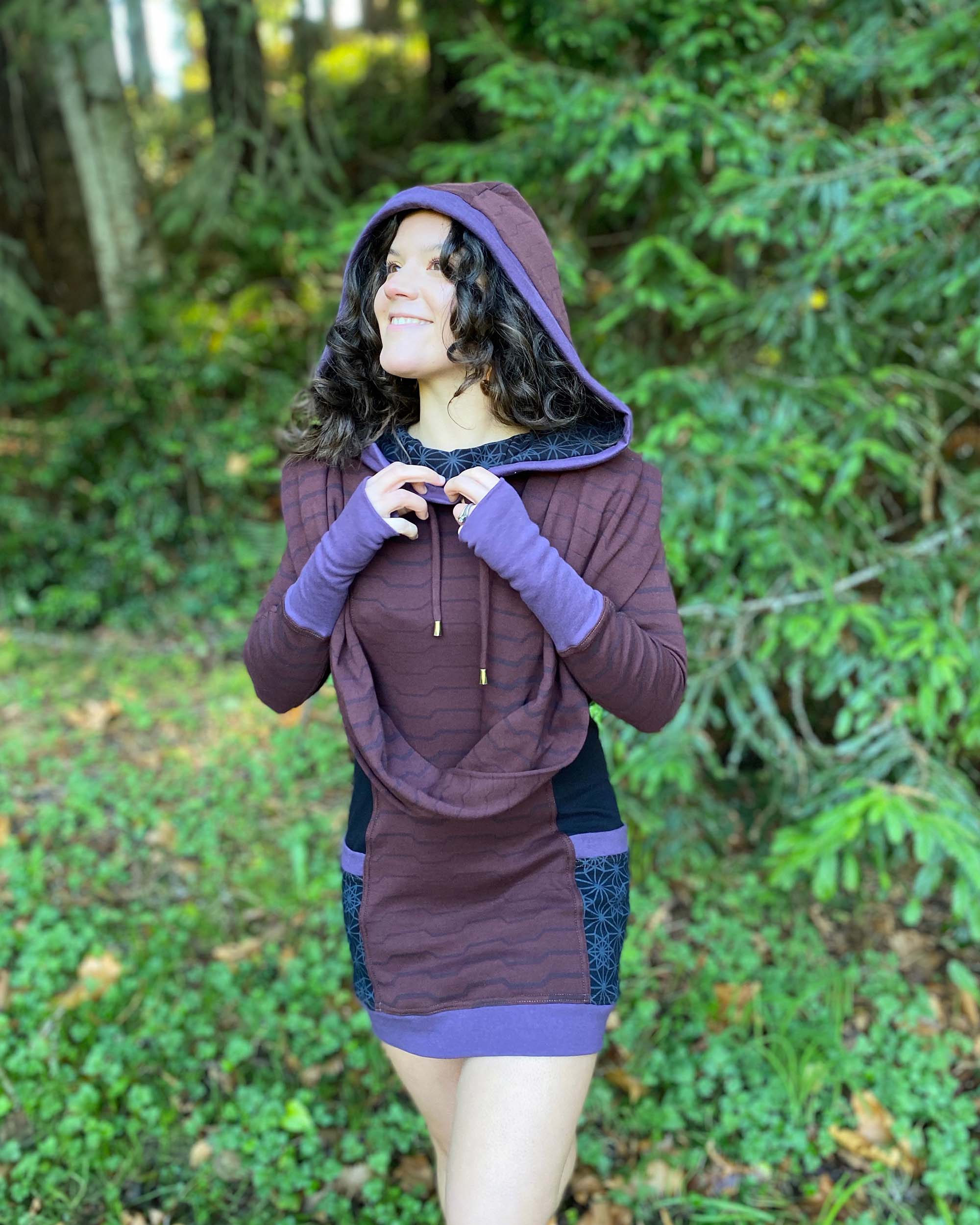 Organic cotton hooded tunic dress, reddish brown with geometric print, front left side view on model.