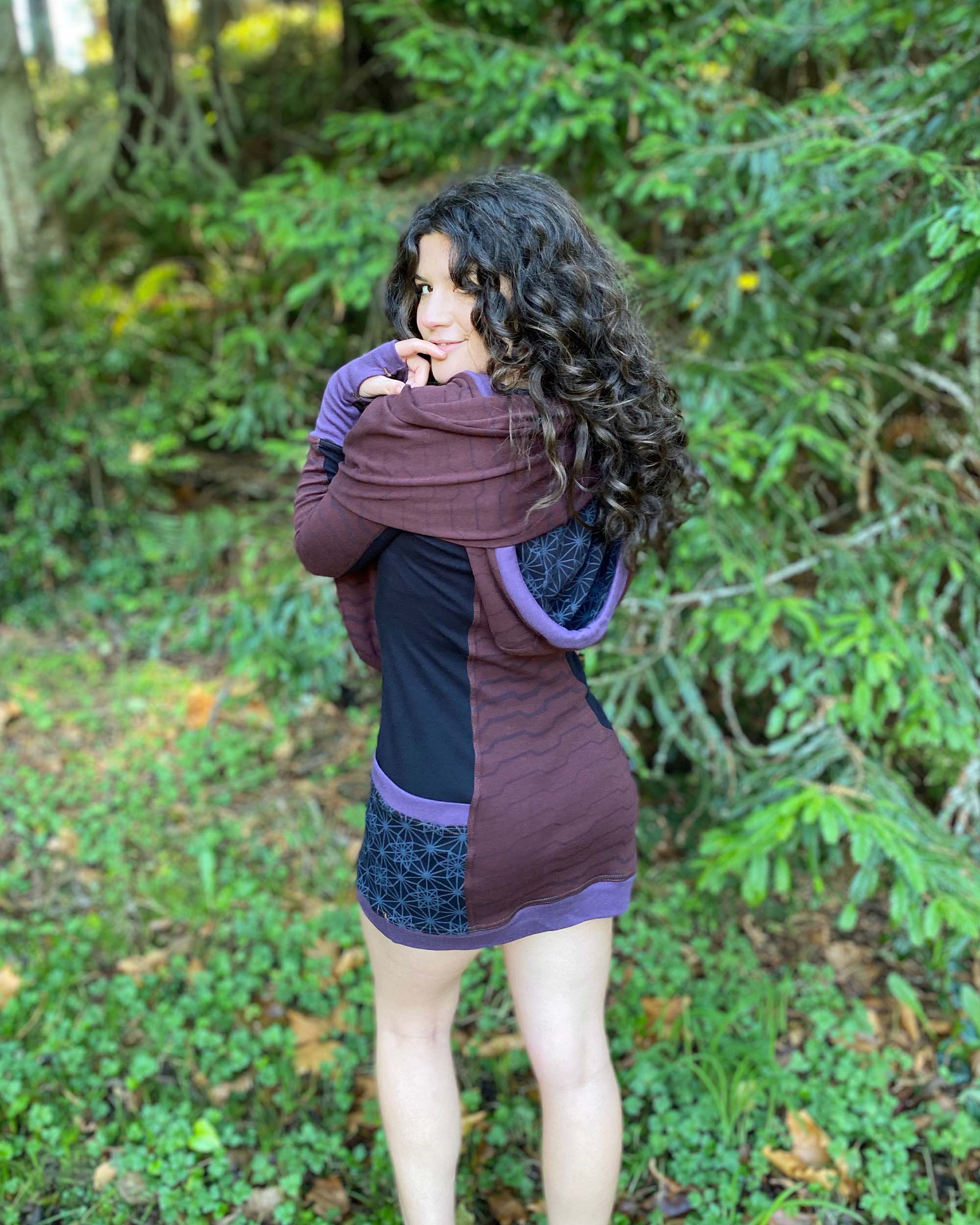 Organic cotton hooded tunic dress, reddish brown with geometric black fabric accents, back view on model.