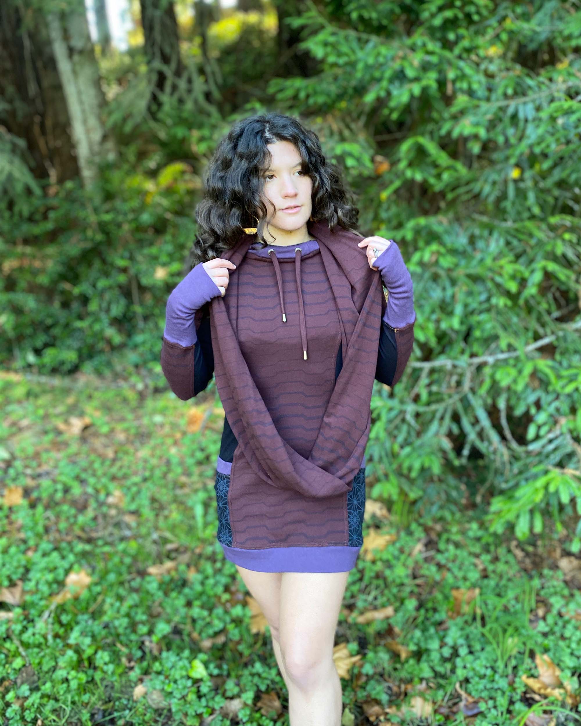 Organic cotton hooded tunic dress and scarf in reddish brown with geometric black fabric accents, front view on model.