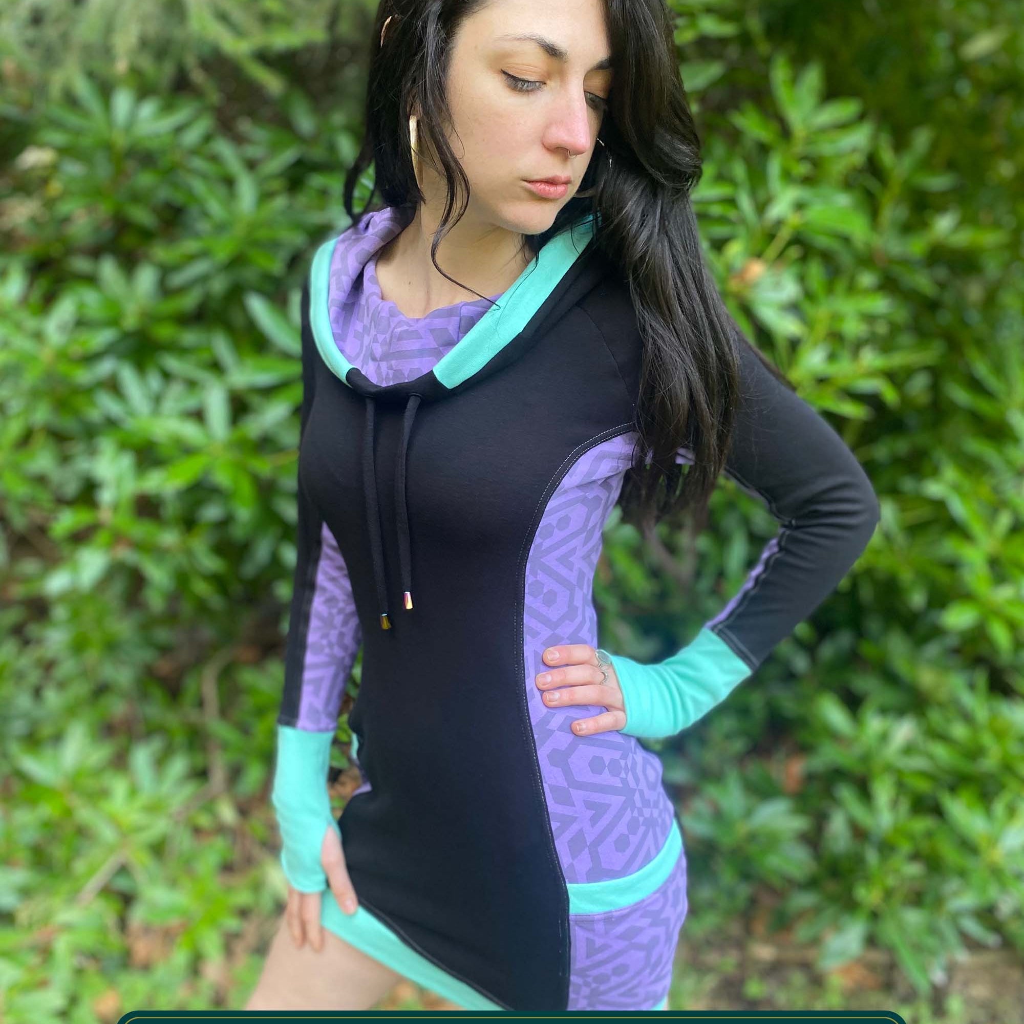 Organic cotton hooded tunic dress, black and lavender fabric with geometric print, left side view on model.