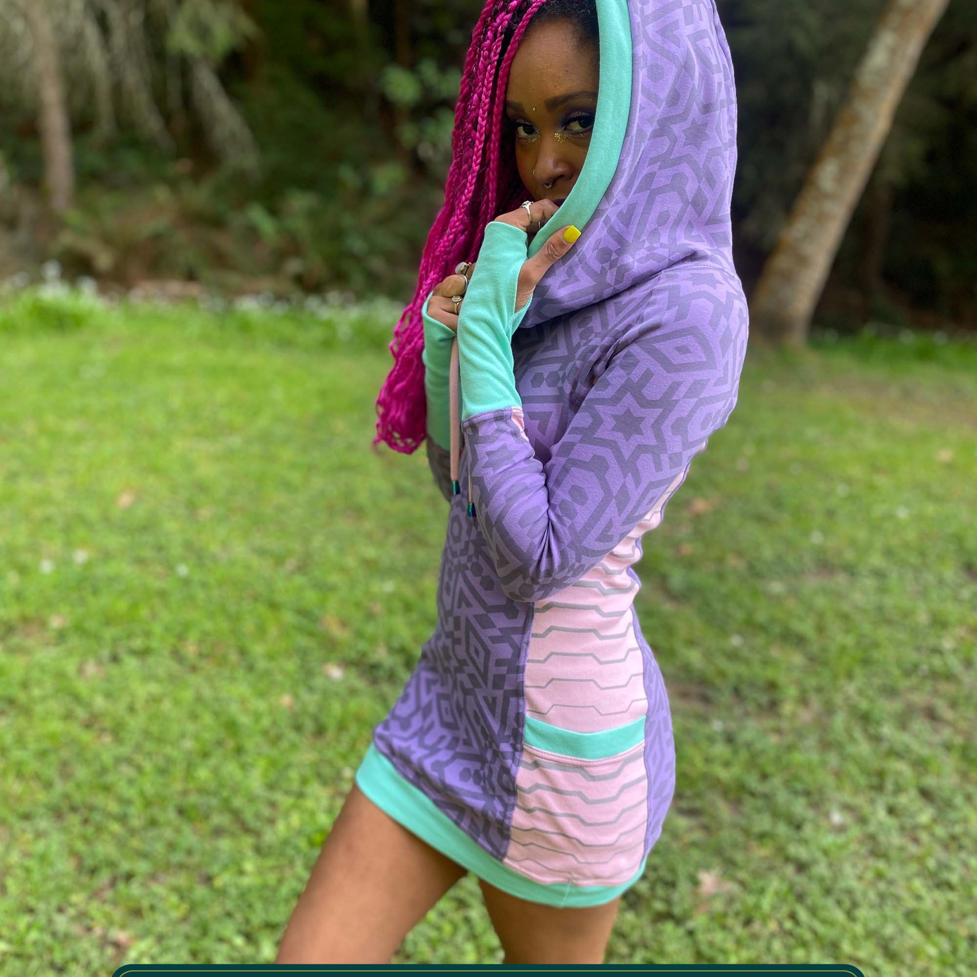 Organic cotton hooded tunic dress, lavender and pink fabric with geometric print, left side view on model.