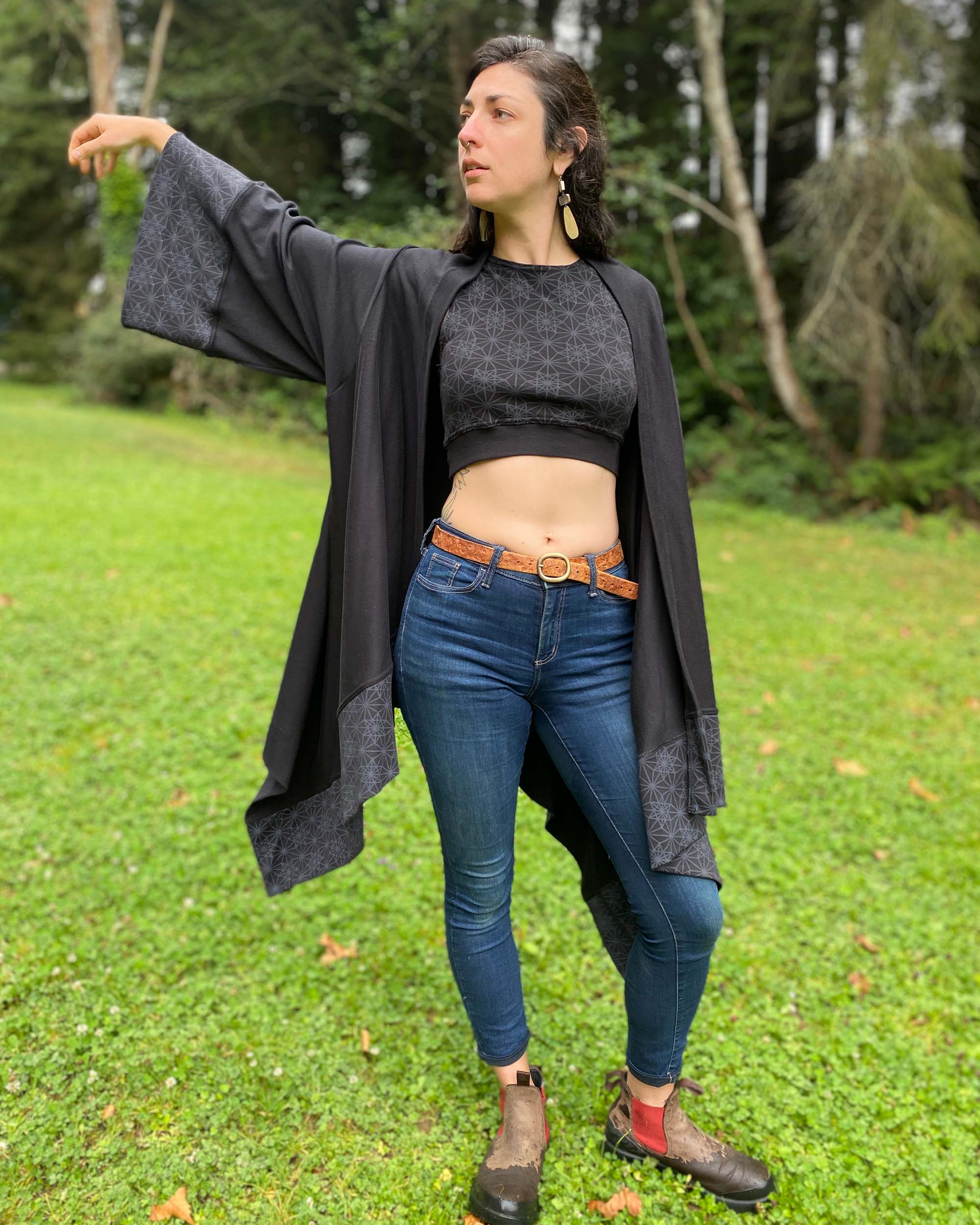 Organic cotton kimono, black fabric with geometric printed accents, front view on female model in nature.