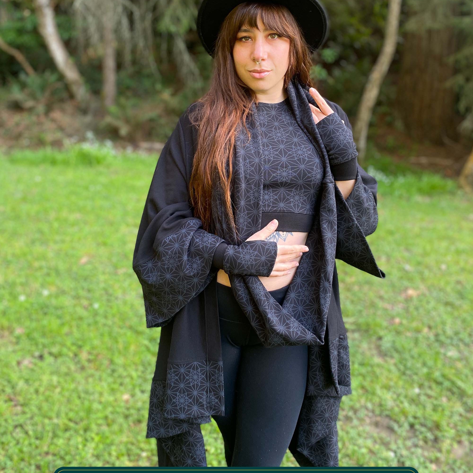 Organic cotton kimono, black fabric with geometric print accents, front view on female model in nature.