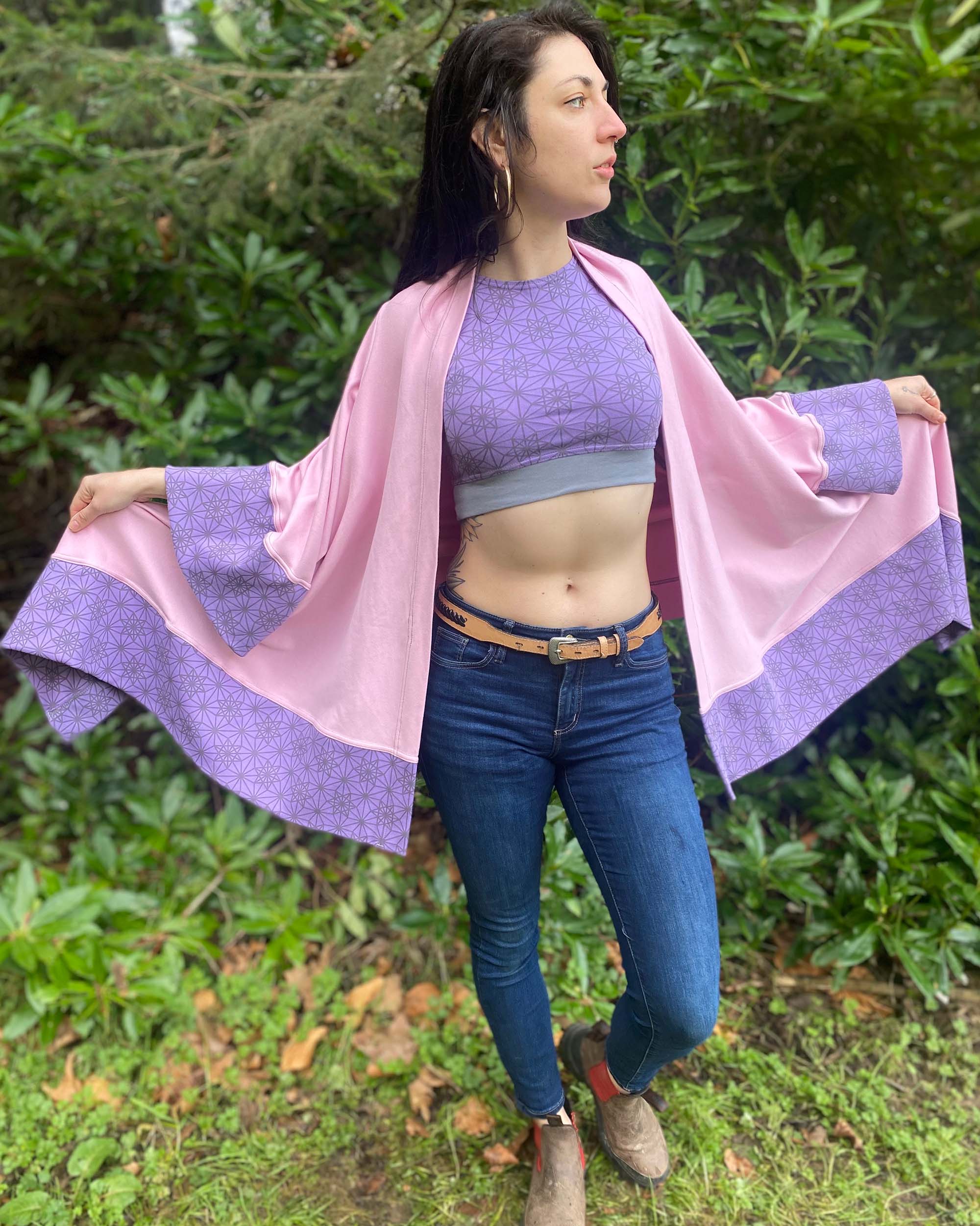 Organic cotton kimono, pink with geo print and lavender accents, front view worn by female model in nature.