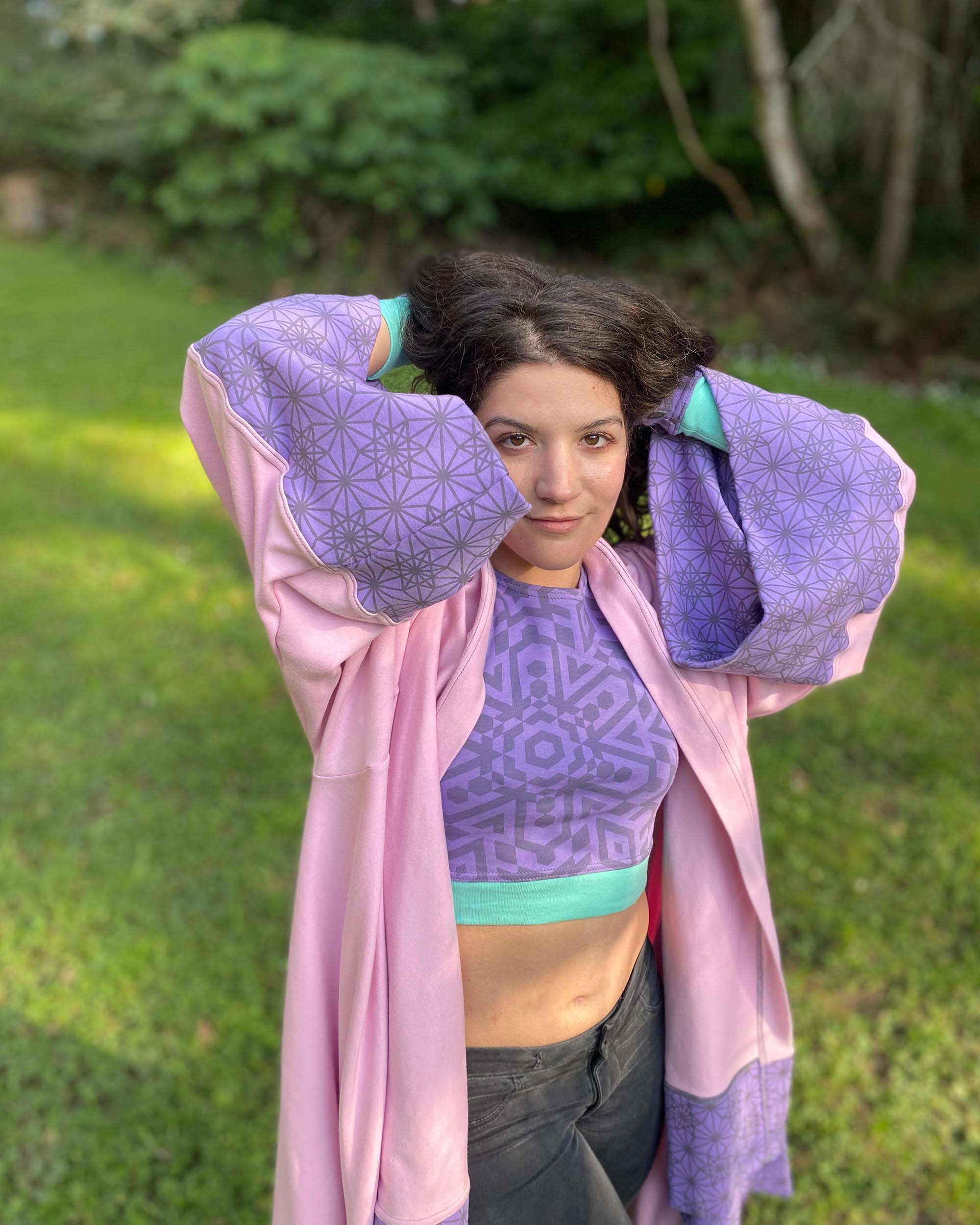Organic cotton pink kimono with geo print lavender fabric accents, front view on female model in nature.