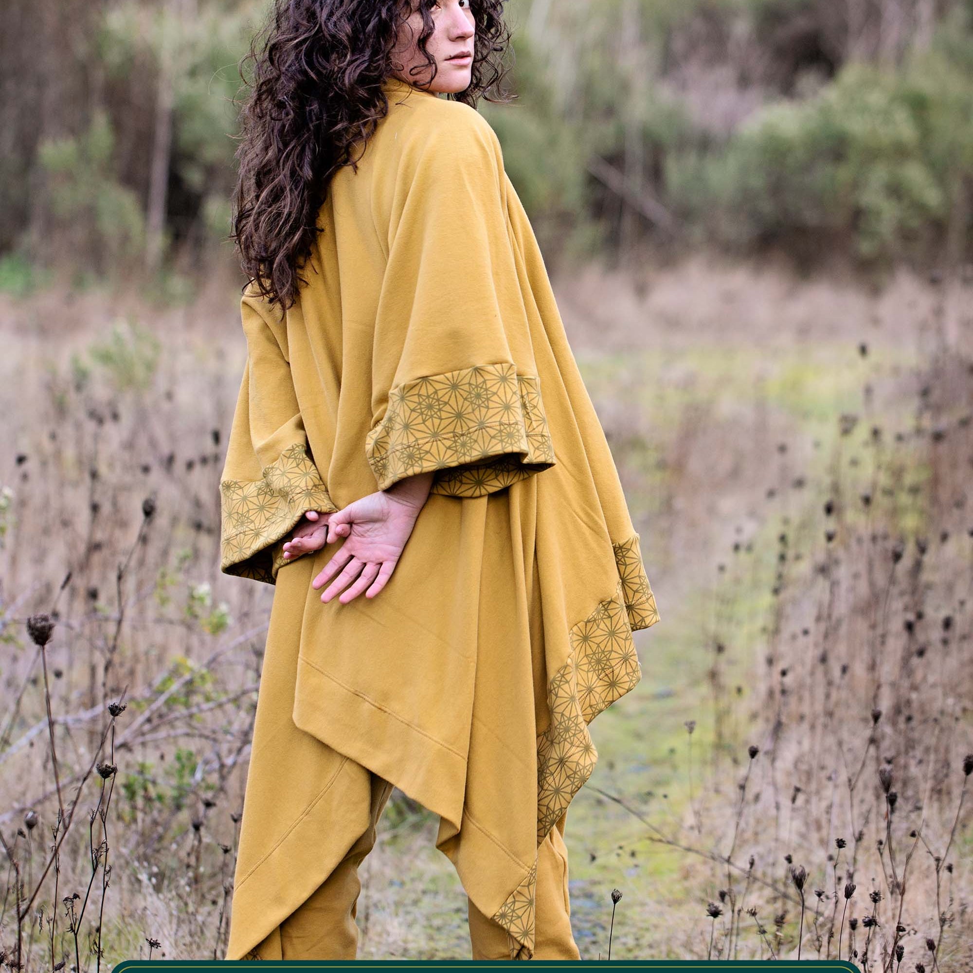Organic cotton kimono, yellow fabric with geometric print accents, back view on model in nature.