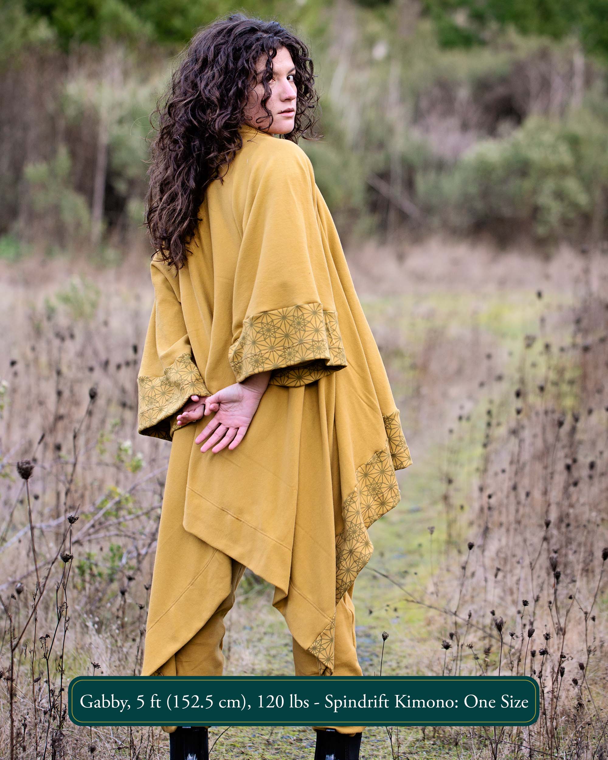 Organic cotton kimono, yellow fabric with geometric print accents, back view on model in nature.