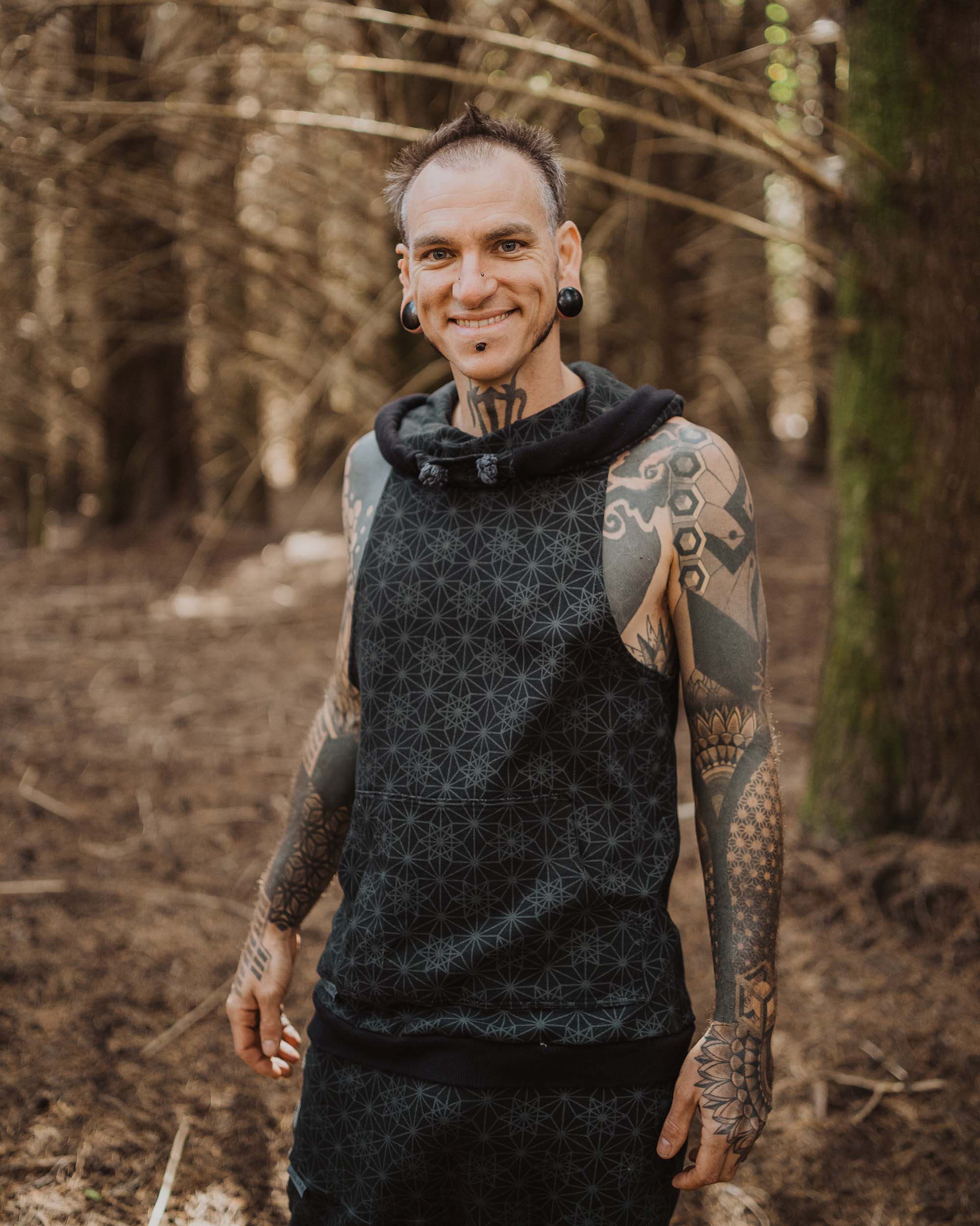 Organic cotton matching hooded tank top and shorts, black fabric with geometric print, front view on male model.