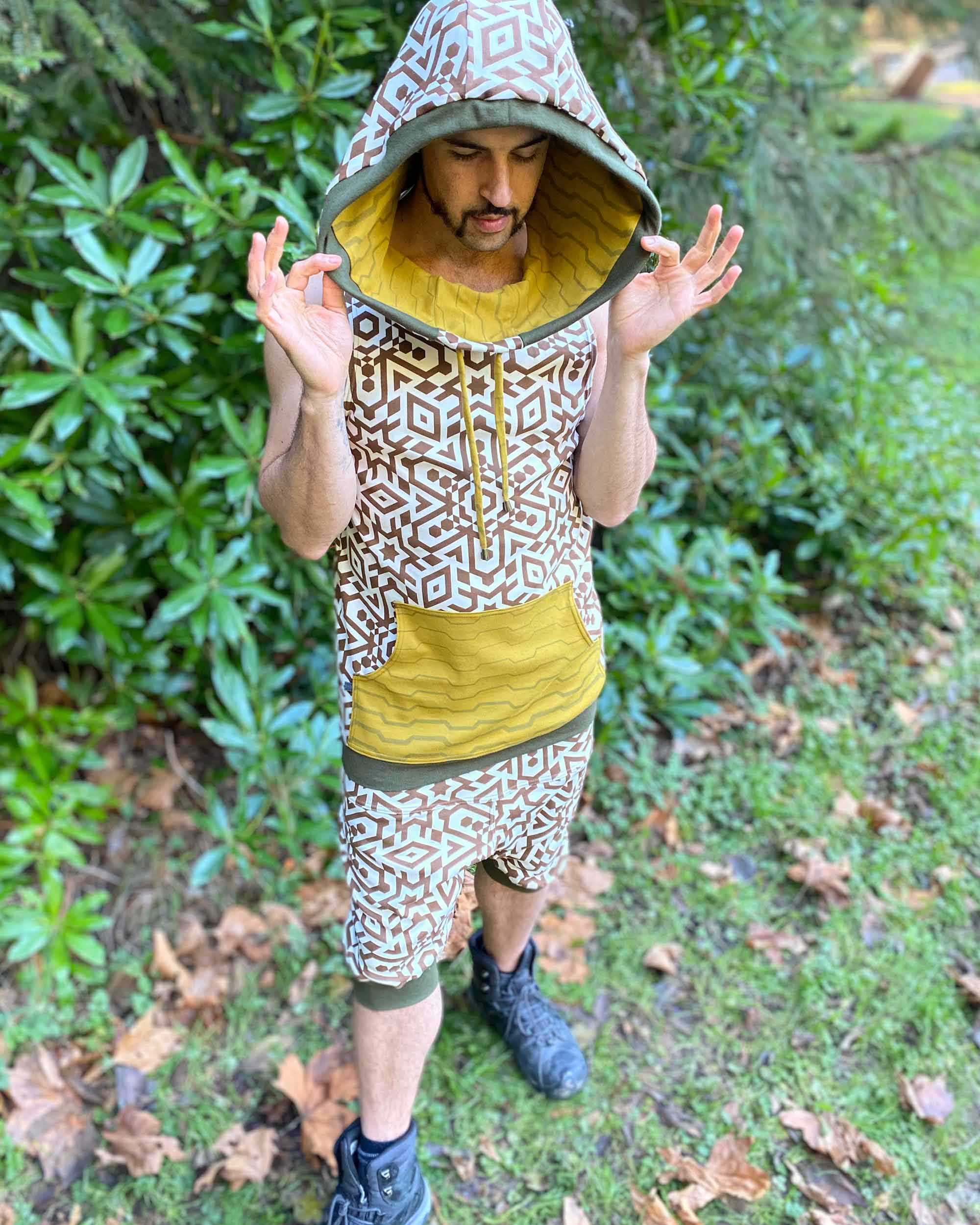 Organic cotton hooded tank top, un-dyed fabric with brown geometric print, front view on male model, hood up.