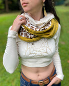 Un-dyed and yellow organic cotton infinity scarf with geometric prints, front view on female model.