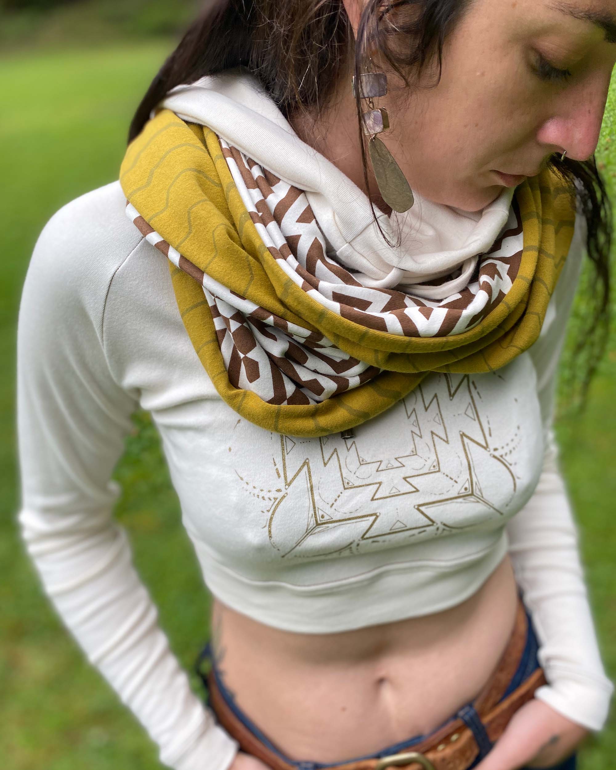 Un-dyed and yellow organic cotton infinity scarf with geometric prints, detail view on female model.