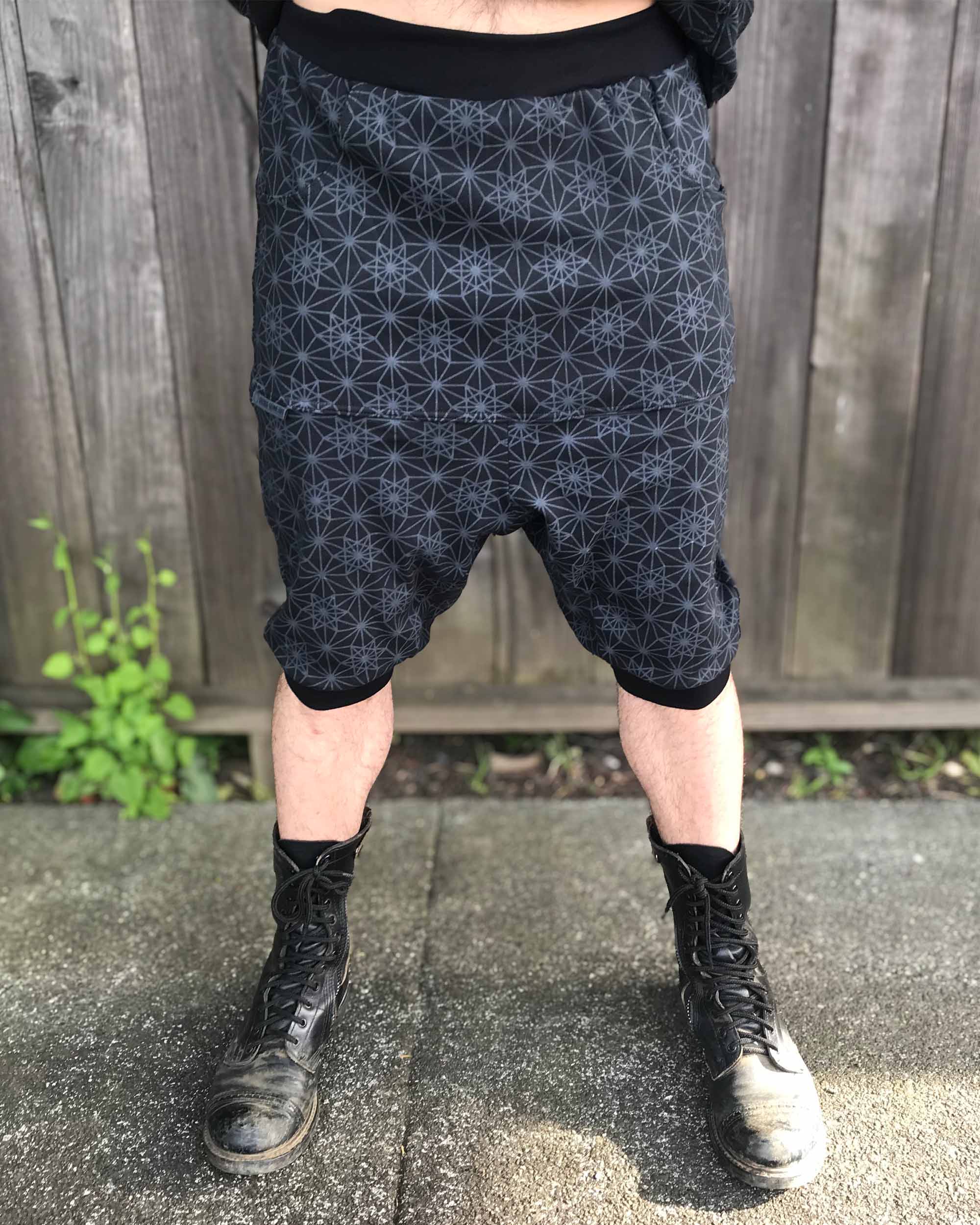 Organic cotton drop crotch shorts, black with geometric fabric print, front view on model.