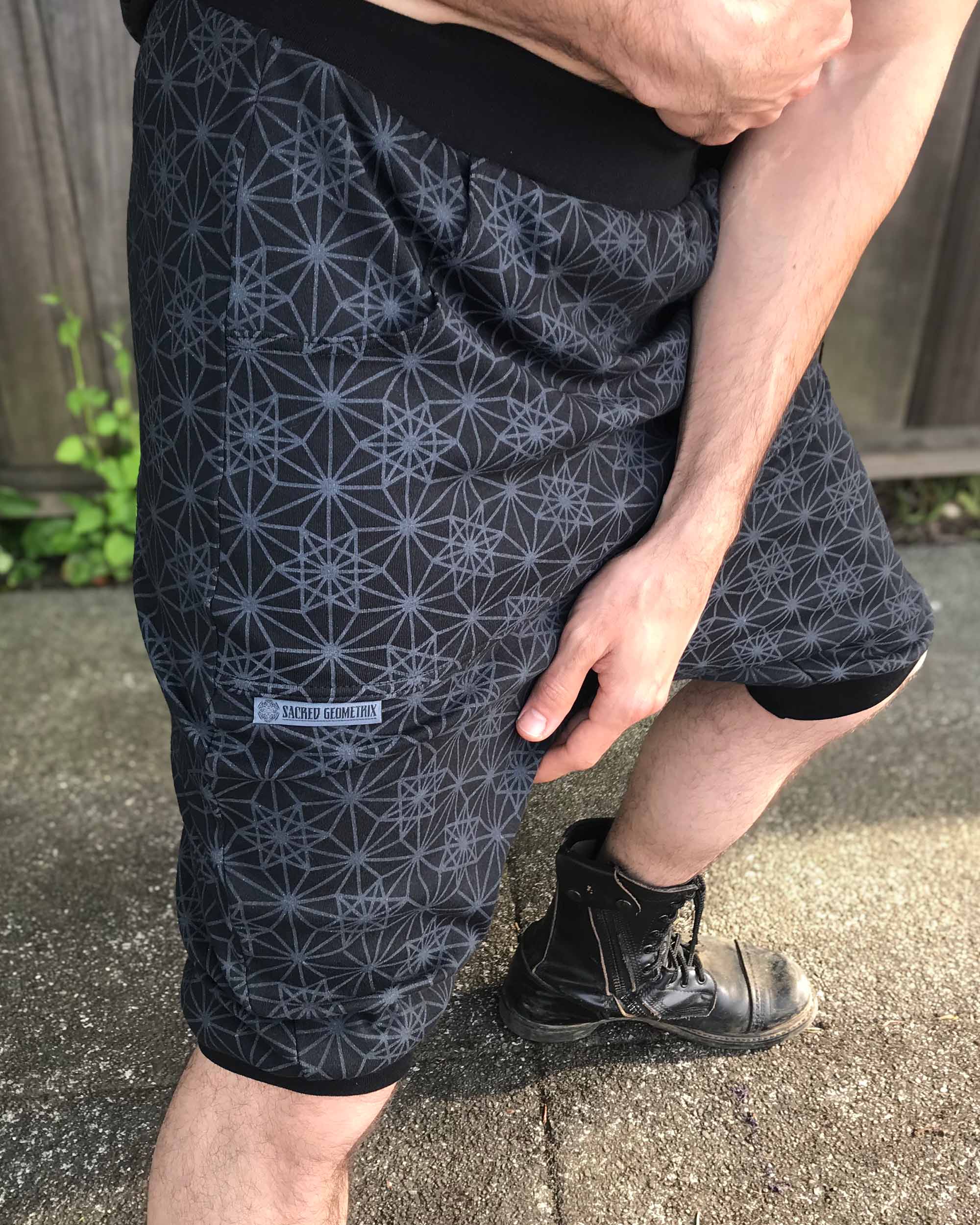 Organic cotton drop crotch shorts, black with geometric fabric print, close up view on model.
