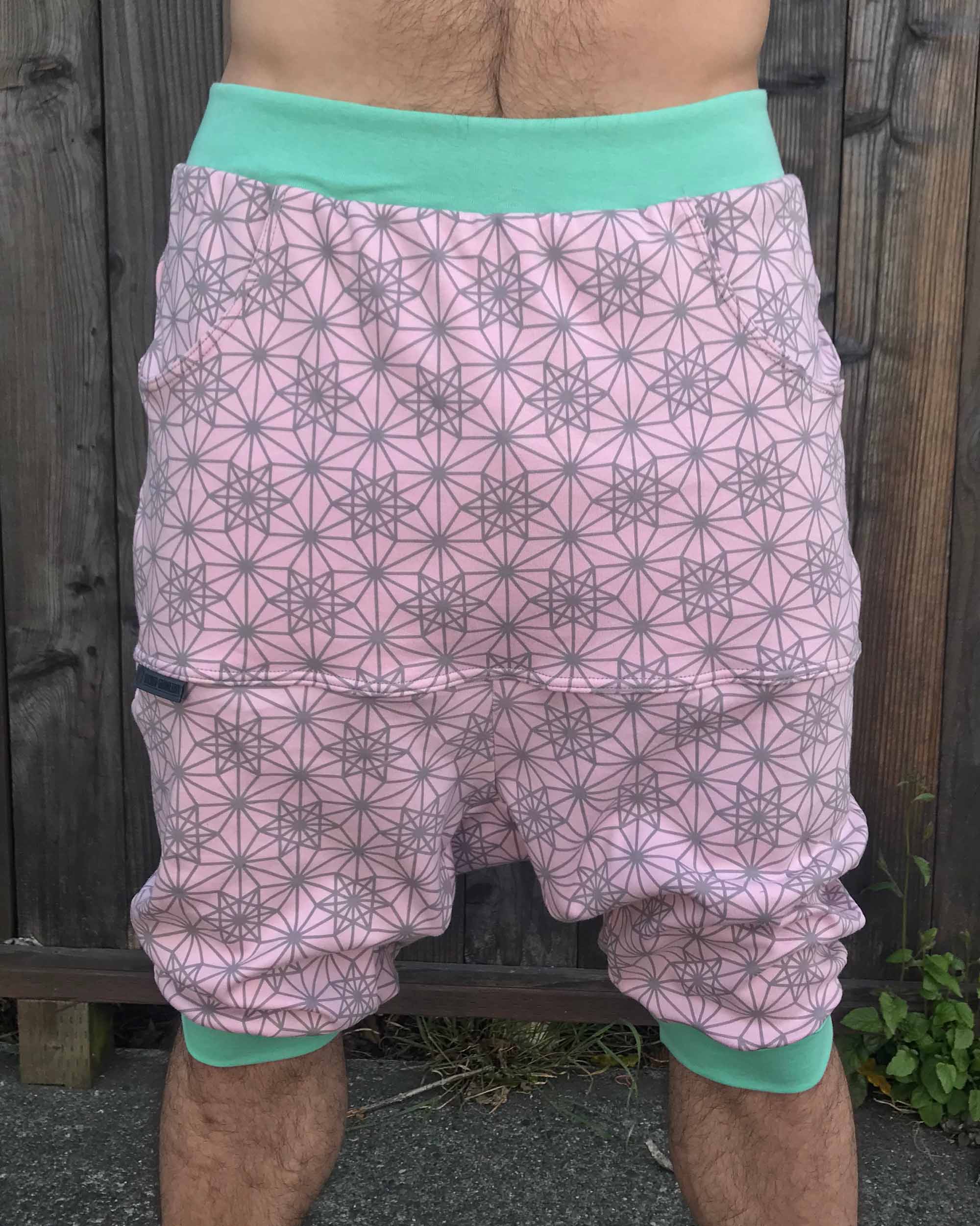 Organic cotton drop crotch shorts, pink with geometric fabric print, front view on model.