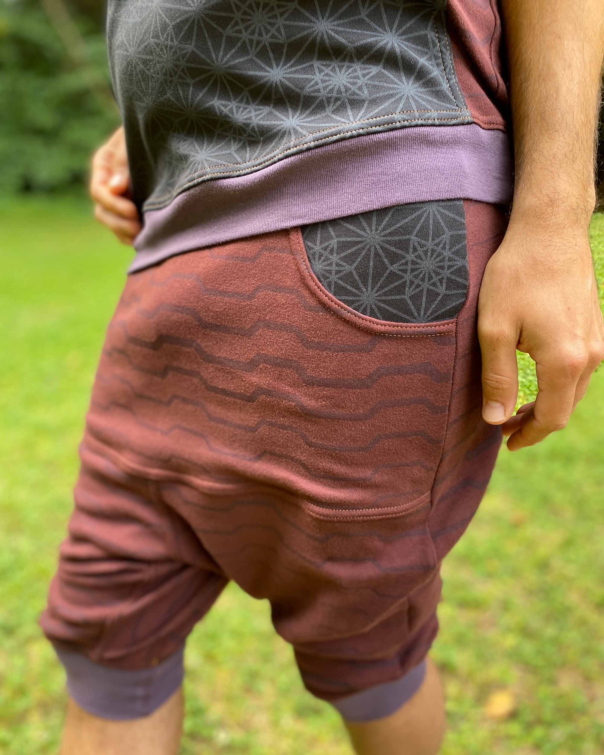 Organic cotton drop crotch shorts, brown fabric with geo print, close up of pocket.
