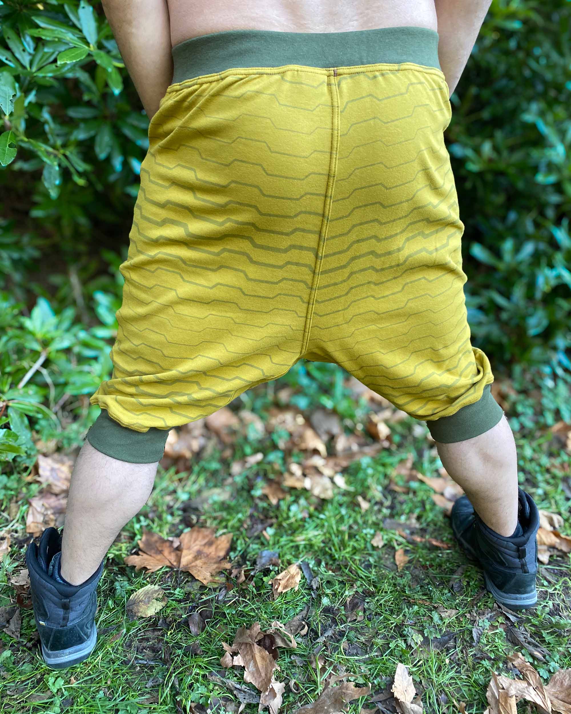 Organic cotton drop crotch shorts, yellow fabric with stripe print, back side view on male model.