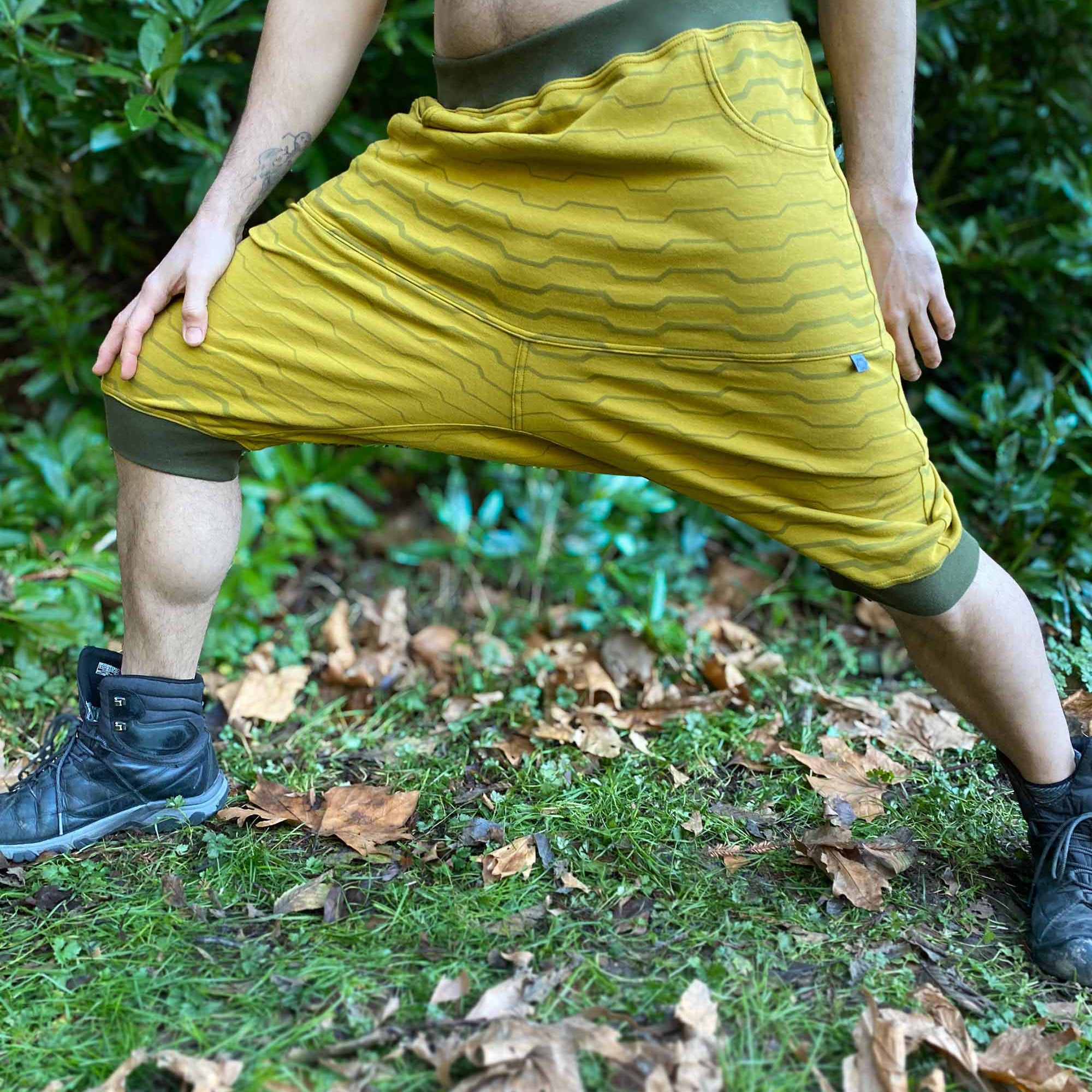Organic cotton drop crotch shorts, yellow fabric with geometric stripes, front view on male model.