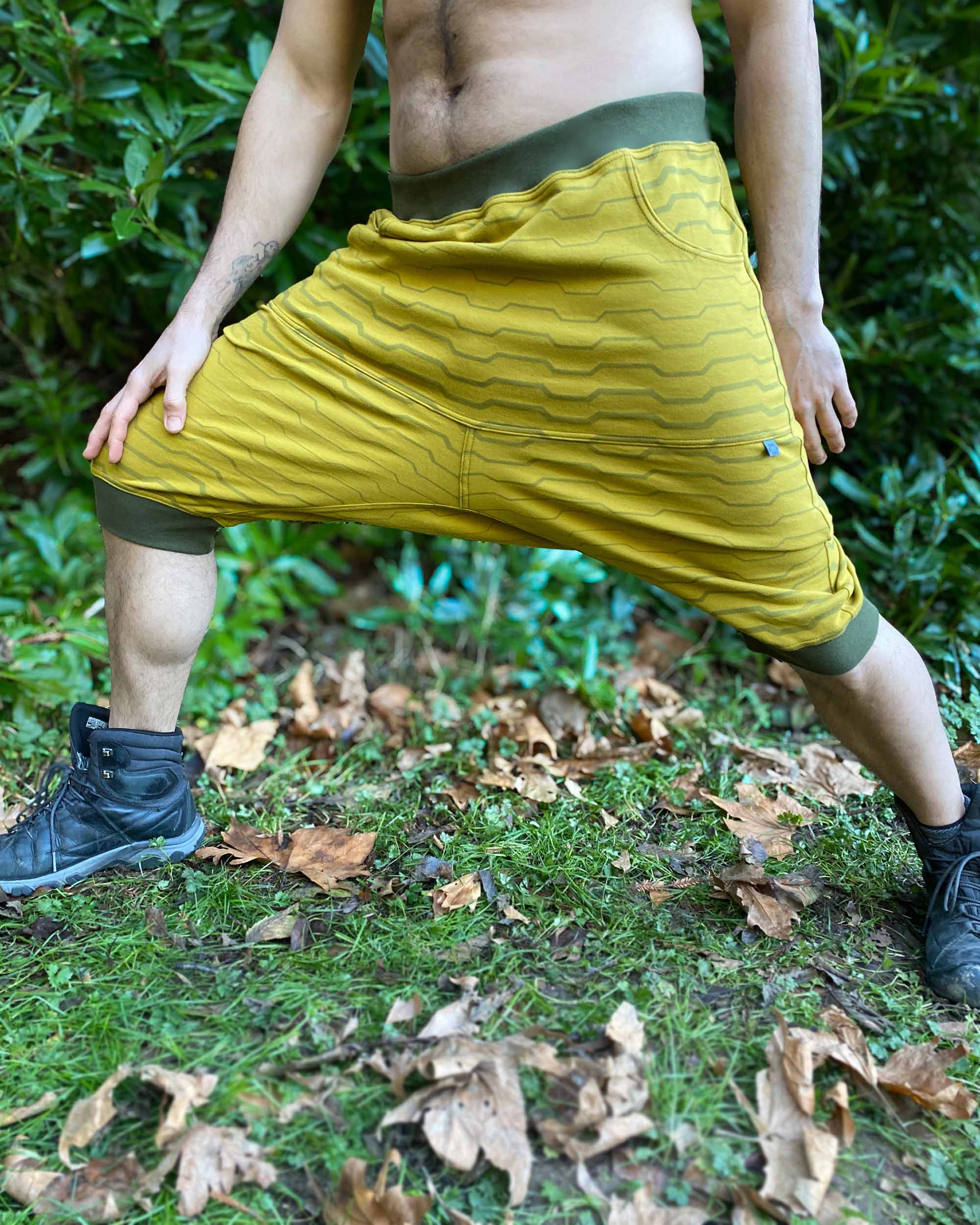 Organic cotton drop crotch shorts, yellow fabric with geometric stripes, front view on male model.