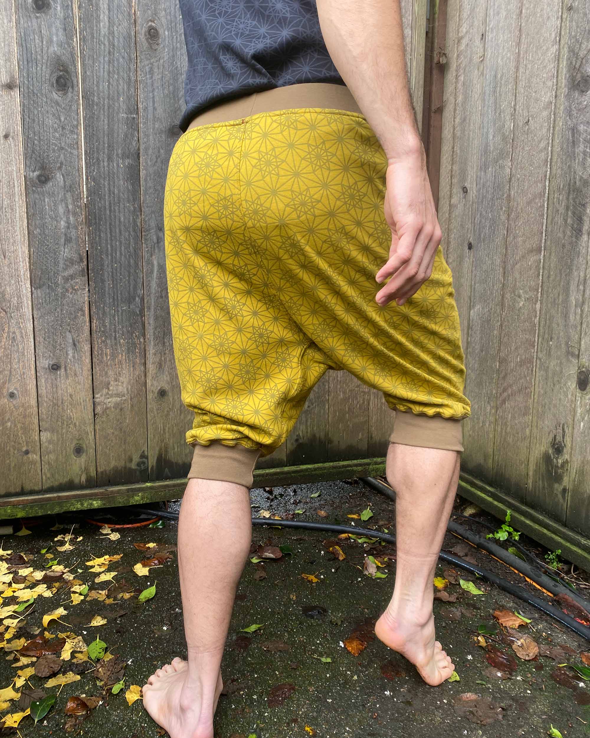 Organic cotton drop crotch shorts, yellow fabric with geometric print, back right side view on model.